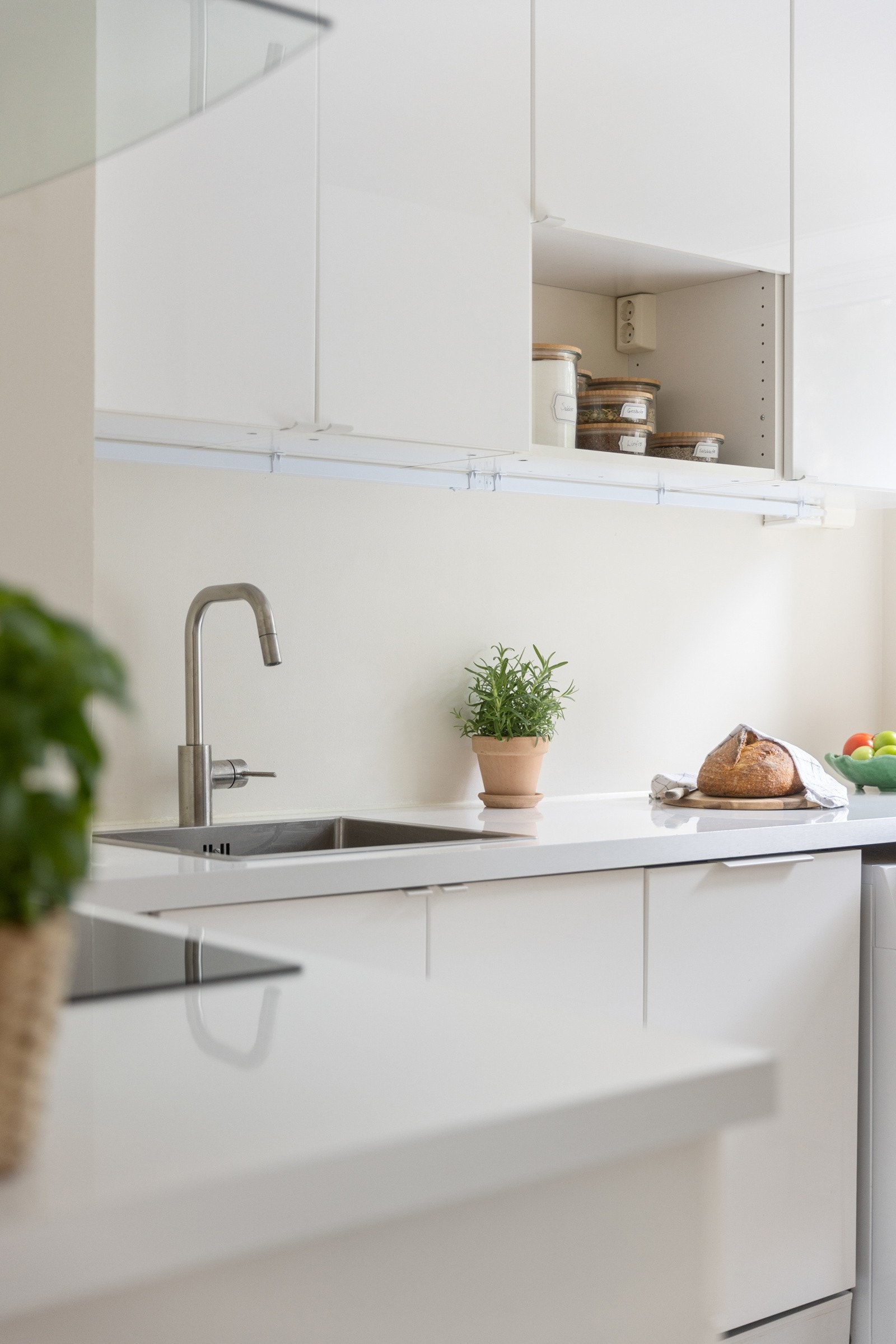 Kjøkkeninnredning med hvite glatte høyglansfronter og pene benkeplater i laminat. Galleribilde