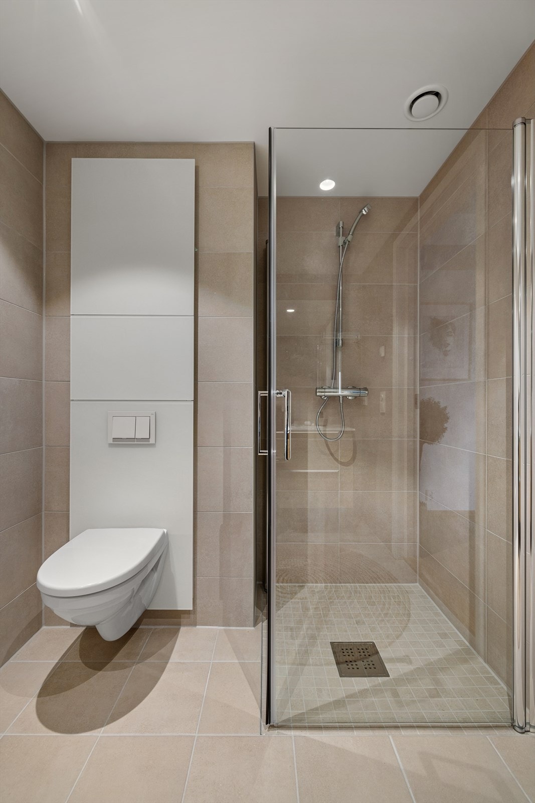 Badet er utstyrt med vegghengt toalett, dusjhjørne med svingbare glassvegg, baderomsinnredning med nedfelt servant, samt speil. Galleribilde