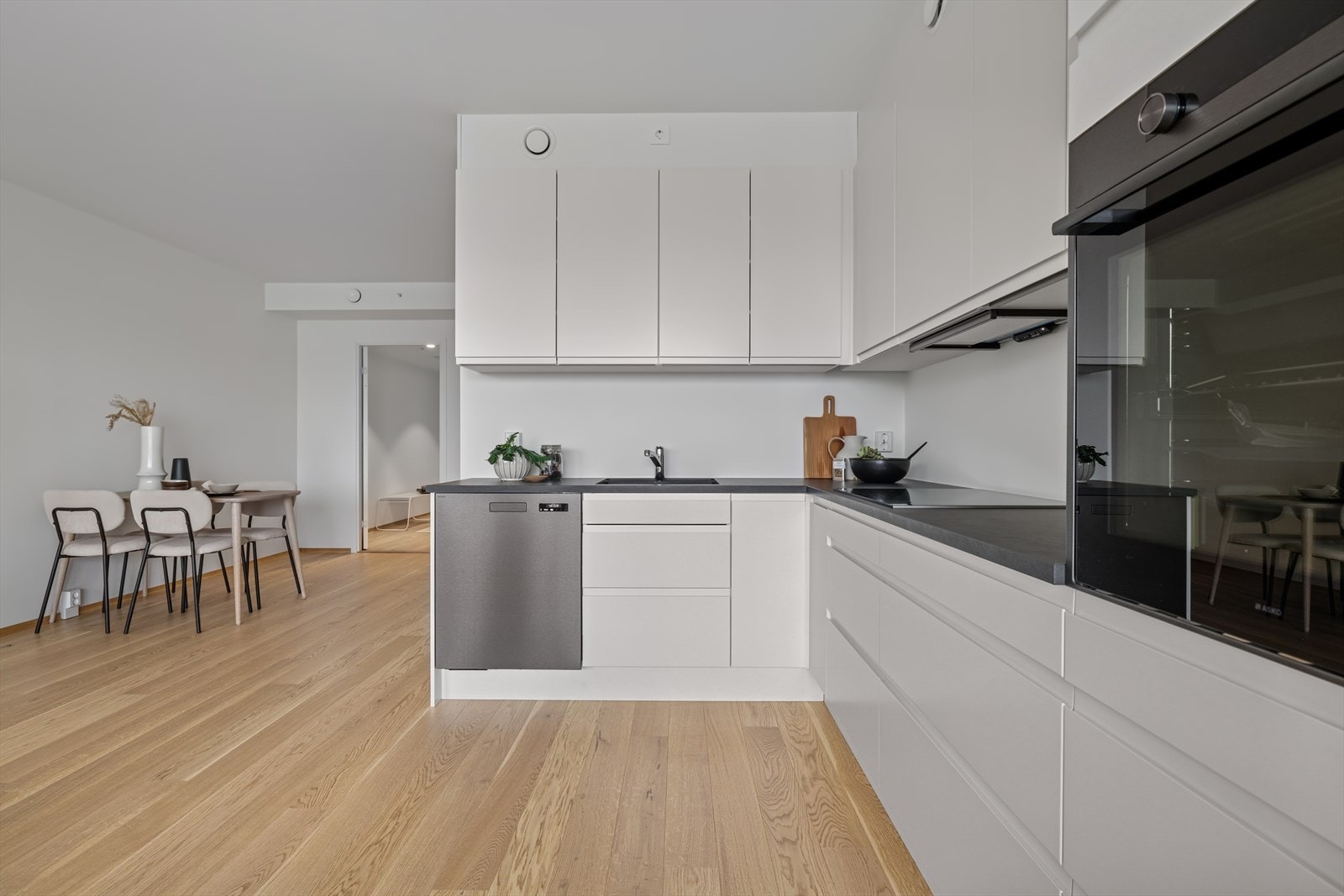 Kjøkkeninnredning med hvite slette fronter og laminat benkeplate. Galleribilde