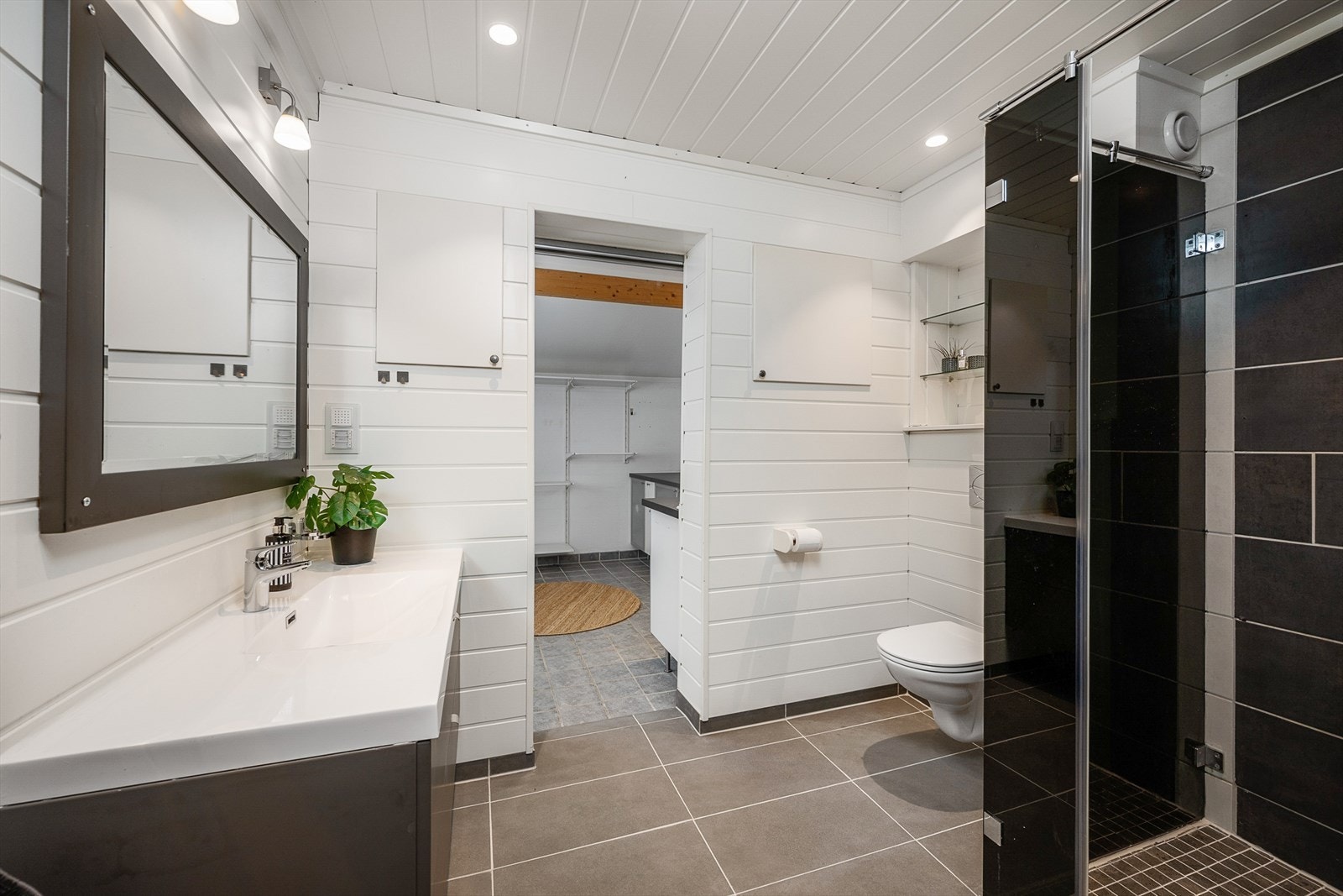 Stilrent bad/wc med tilstøtende vaskerom/bod. Badet har dusj, wc og baderomsinnredning og ligger i boligens hovedetasje. Galleribilde