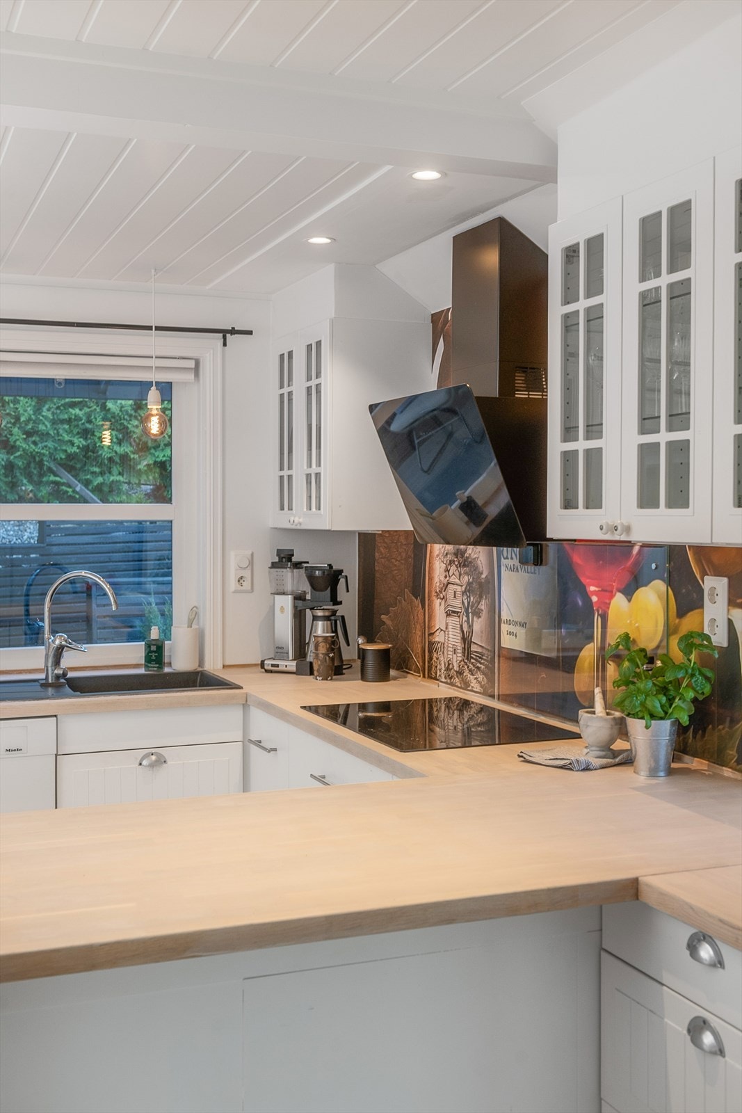 Innredningen har lett profilerte fronter. Overskap har glassdører. Avtrekk over platetopp. Galleribilde