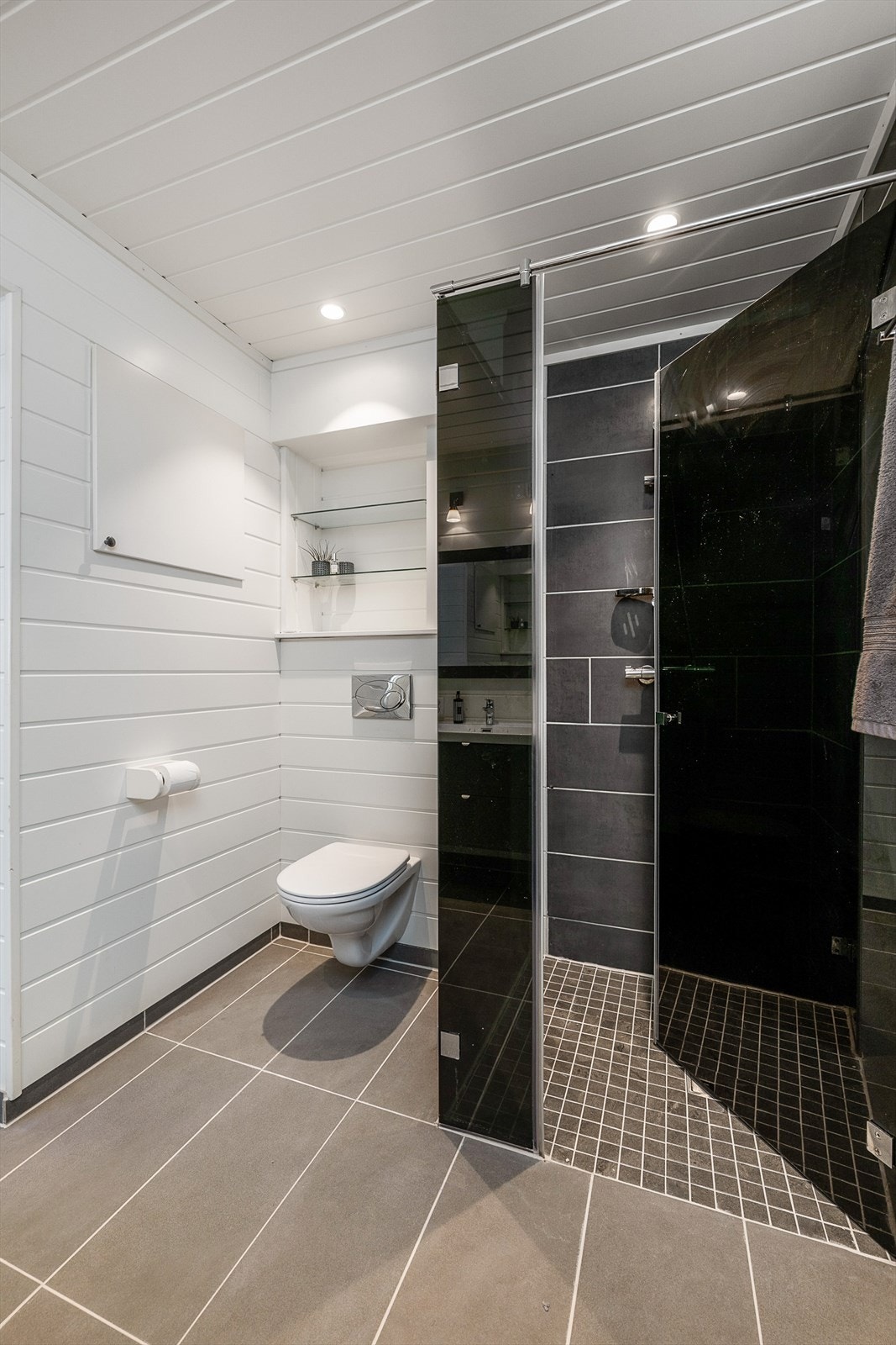 Flislagt dusj og gulv med innfellbar glassdør. Vegghengt WC. Galleribilde