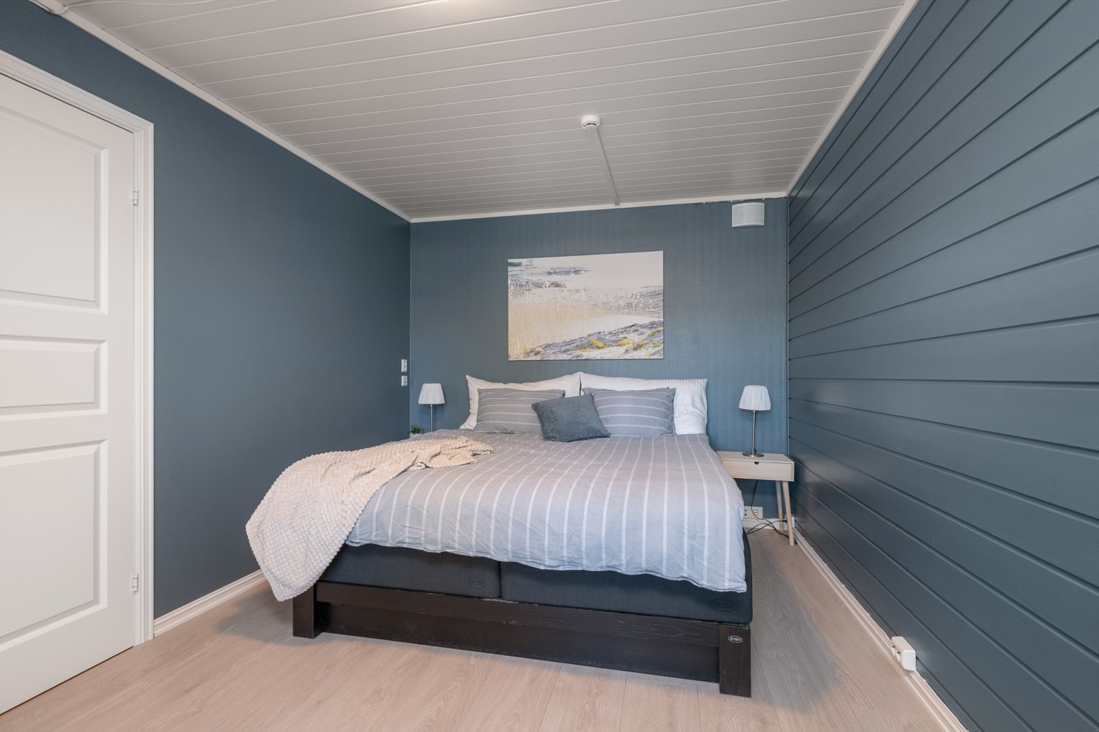 Soverom 2 er innredet med dobbeltseng. Malte overflater i trendy blåtone. Rommet ligger i boligens sokkeletasje. Gulvvarme. Galleribilde