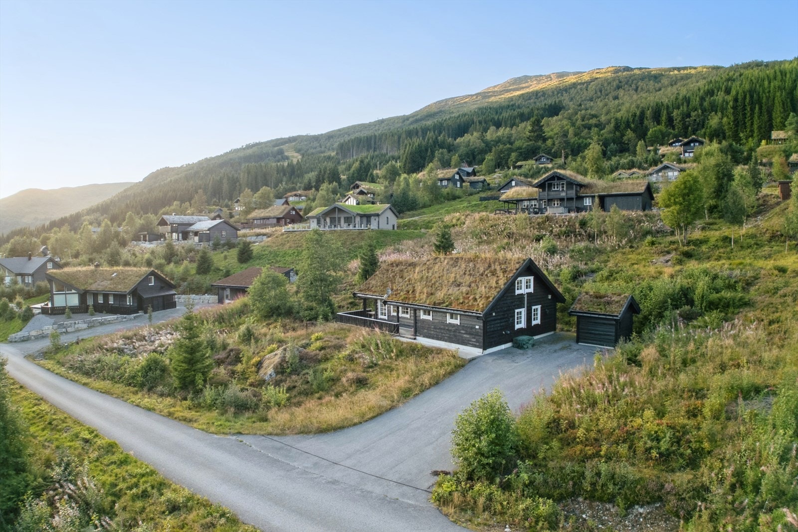 Hytta har asfaltert innkjørsel, ekstra bod/vedlager og mykje luft rundt seg Galleribilde