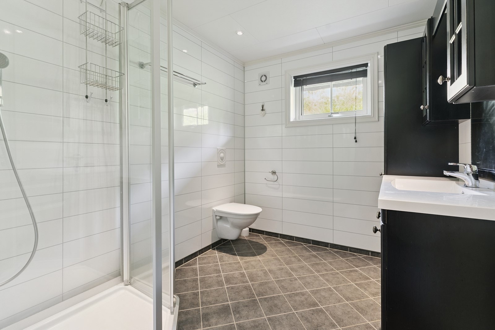 Eit lyst og pent bad med mørk innreiing og gode kvaliteter - vegghengt toalett og stor innreiing med under- over- og sideskap. Galleribilde