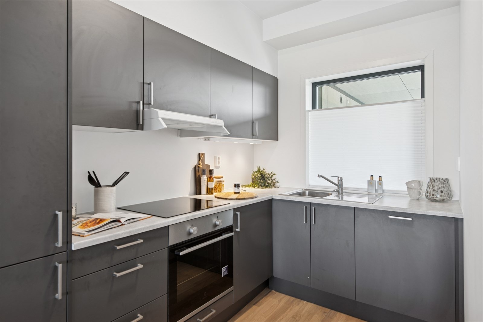 Kjøkken med mørkegrå glatte fronter og integrerte hvitevarer Galleribilde