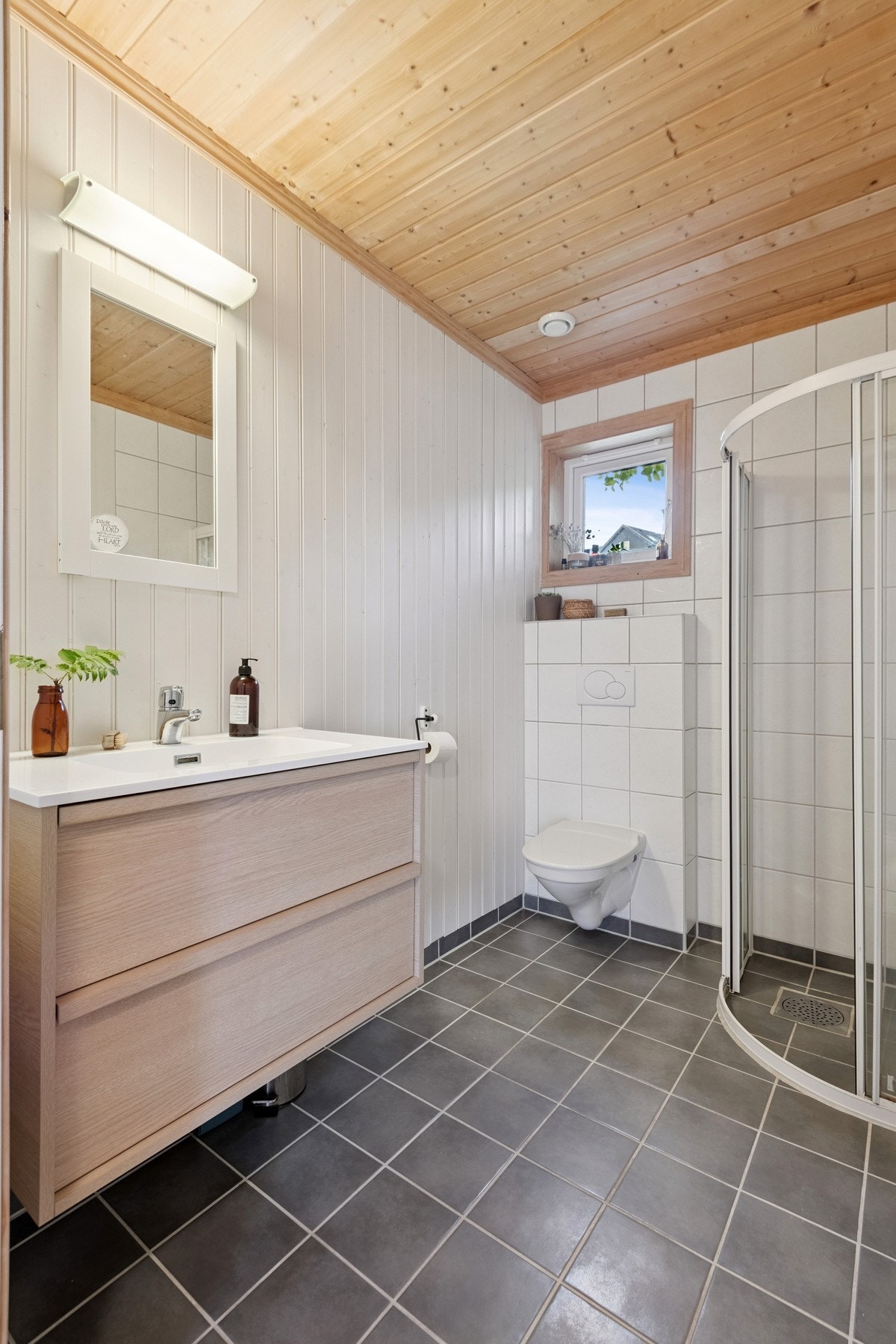 Bad i 1. etasje med vegghengt toalett, dusjhjørne og moderne servantskap. Galleribilde