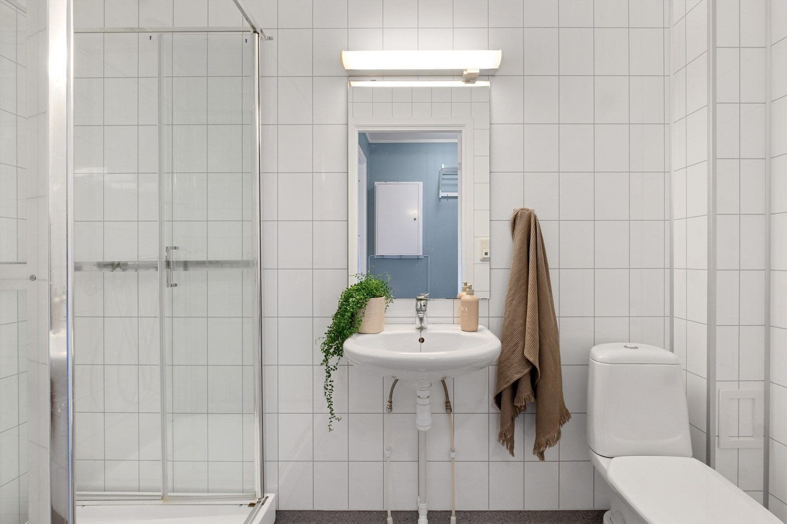 Smakfullt bad med gulvvarme. Frittstående toalett, dusjkabinett og vegghylle. Galleribilde