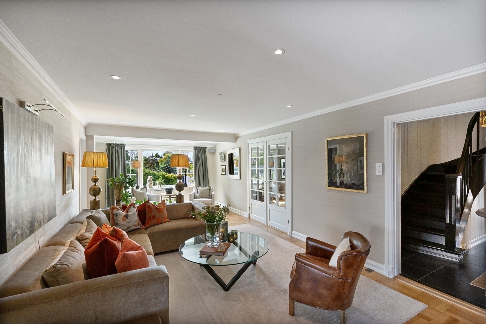 Stuen er smakfullt innredet med en sort, plassbygd bokhylle og tv-reol i trestruktur fra gulv til tak. I tillegg er det god plass til en romslig sofagruppe og annet møblement.