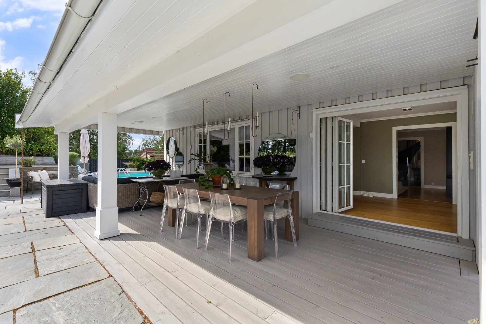 Terrassen har en stor, overbygd del med plass til både loungemøbler, spisegruppe og grill. Her er det innfelte høyttalere, downlights og varmelamper i taket.