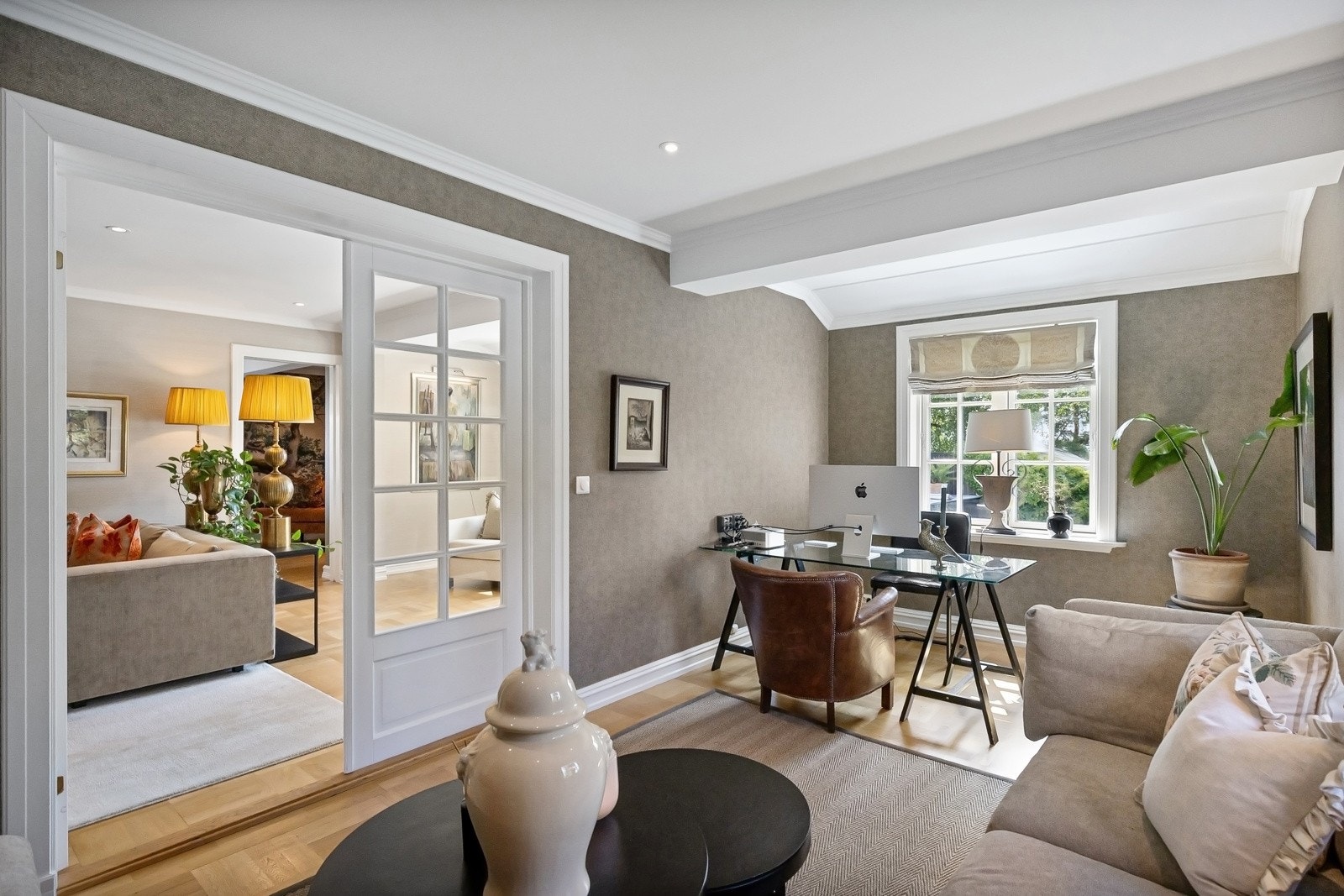 I biblioteket er det vinduer på to sider, vegger kledd i gråbrun tapet fra 2022 og øvrige overflater slik som i stuen.