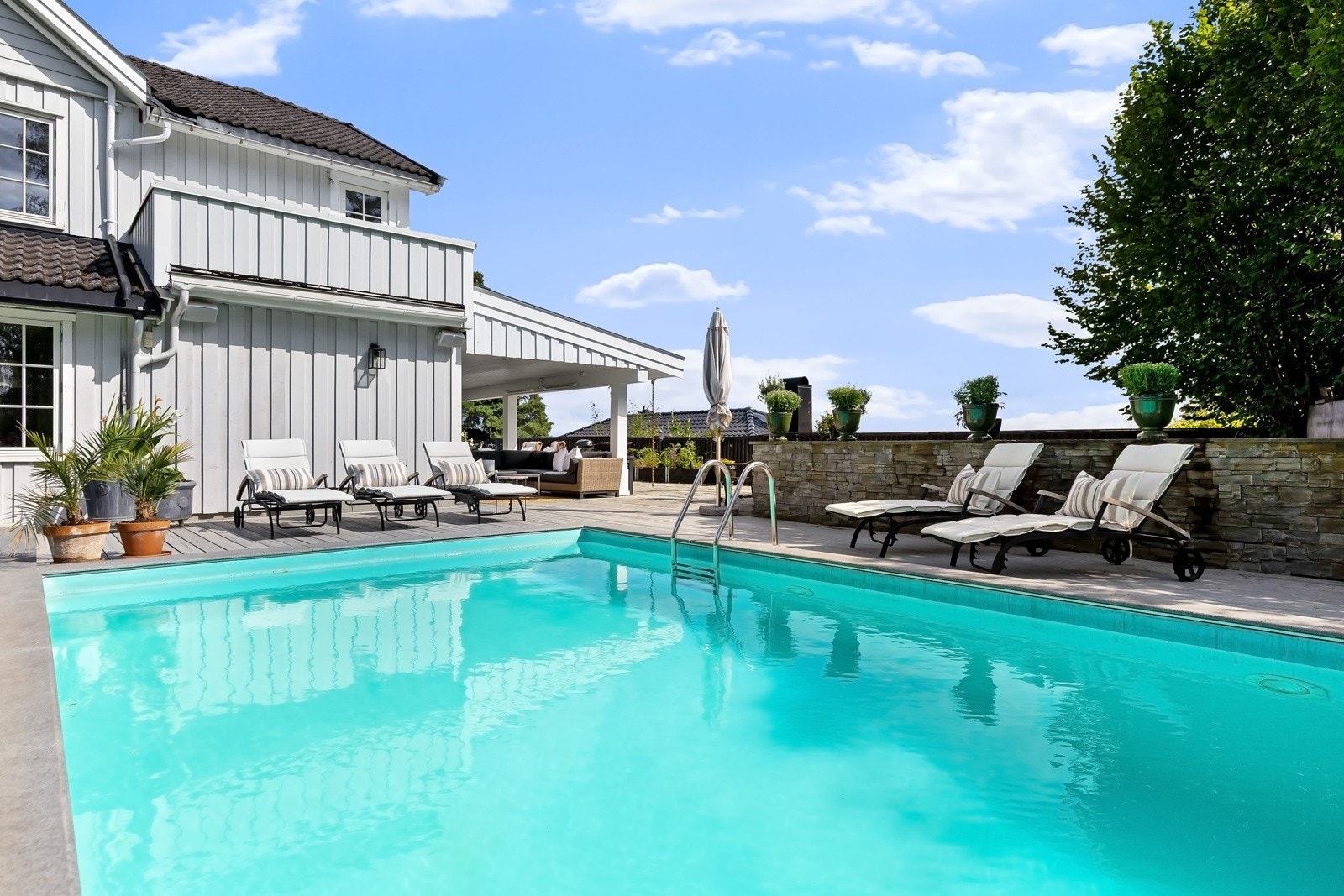 Høyt og usjenert med eget garasjeanlegg under hagen, fantastiske terrasser og et stort svømmebasseng.