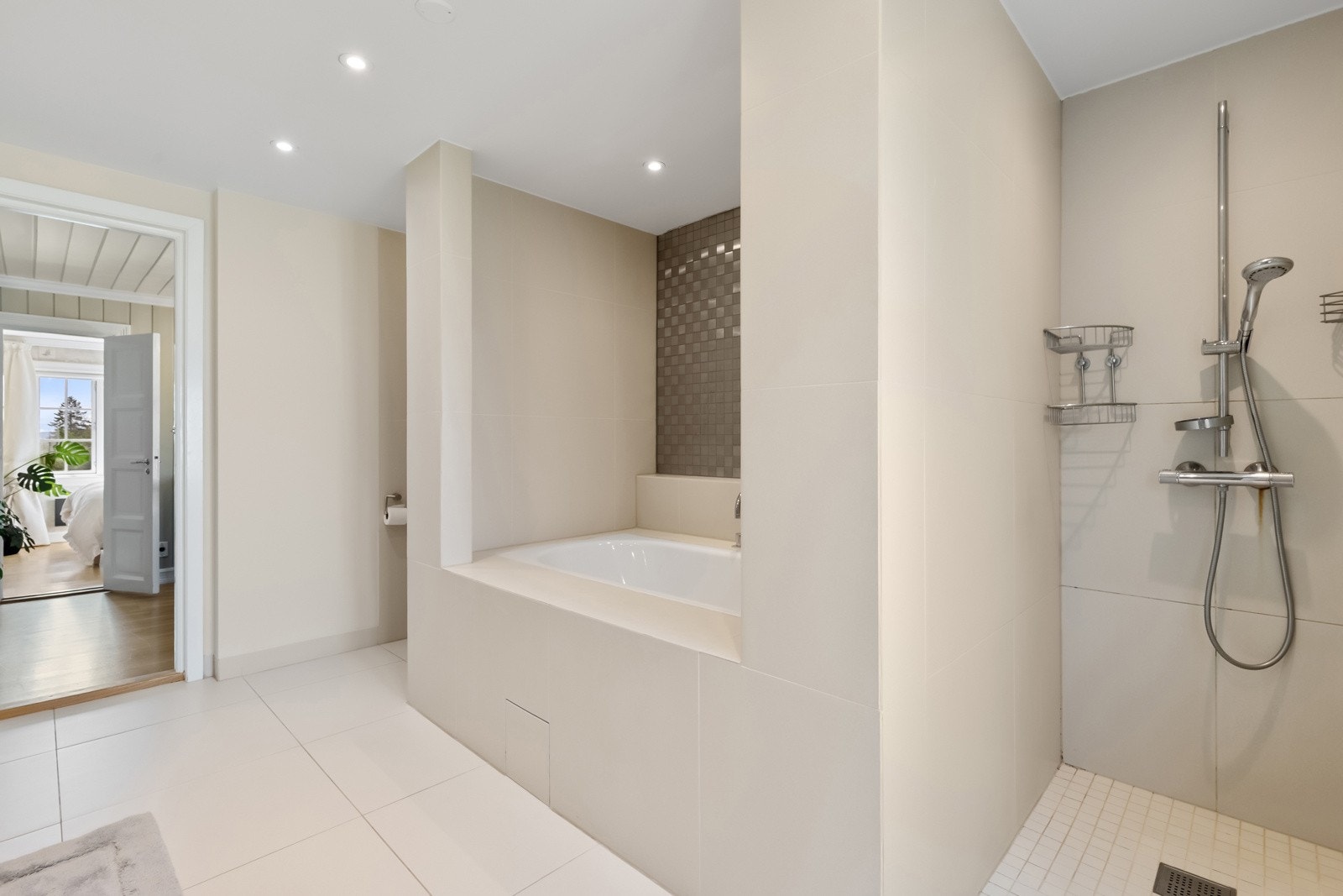 Romslig dusjplass, storformatfliser og gulvvarme samt nisje for vaskesøyle i høyskap.