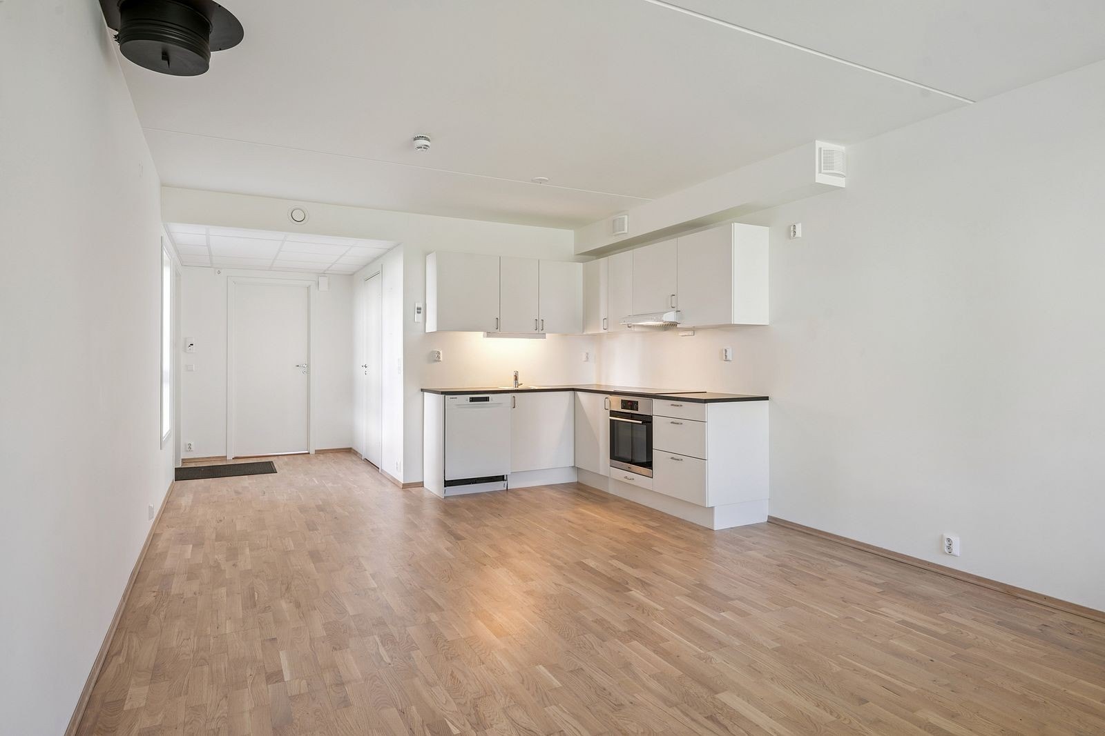 Moderne, hvitt kjøkken med integrerte hvitevarer og plass til spisegruppe. Galleribilde