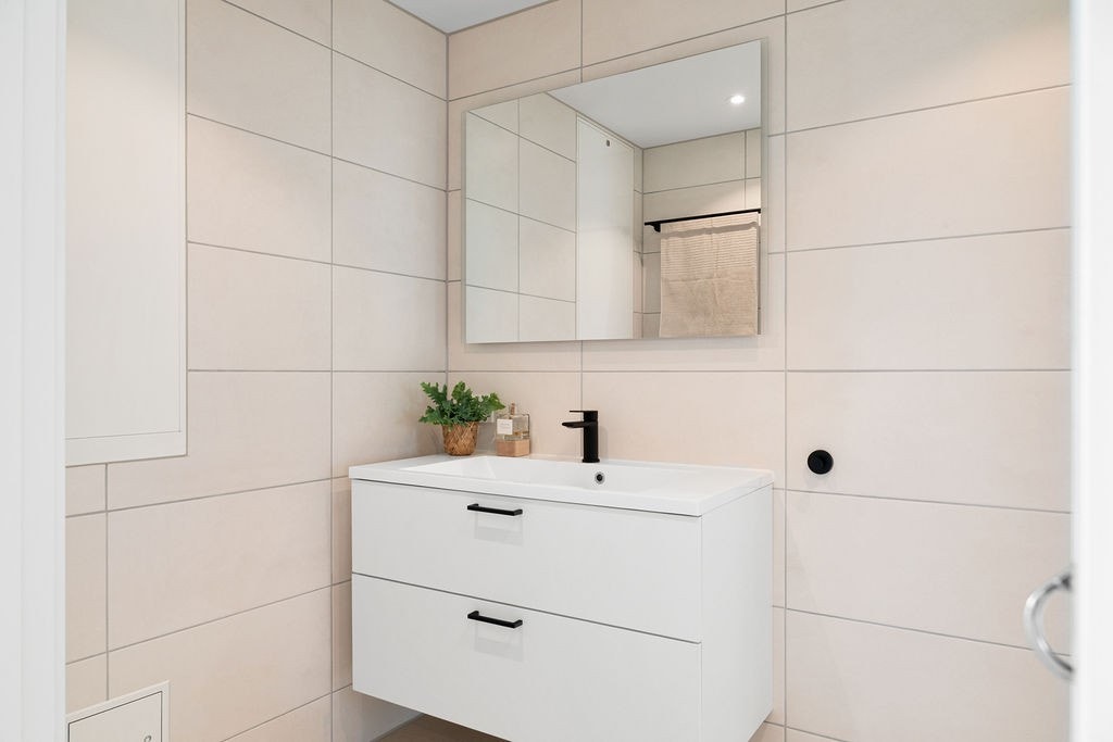 Bad to er et moderne bad med dusj, vegghengt toalett og servant. Galleribilde