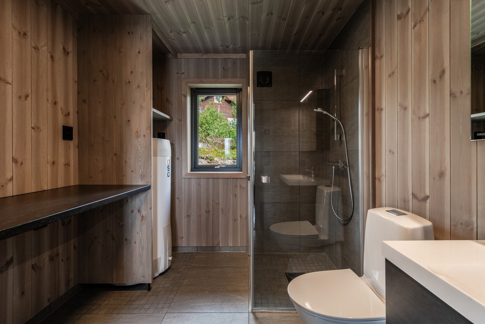 Badet er innredet med dusj, toalett, servant med innredning og opplegg for vaskemaskin. Galleribilde