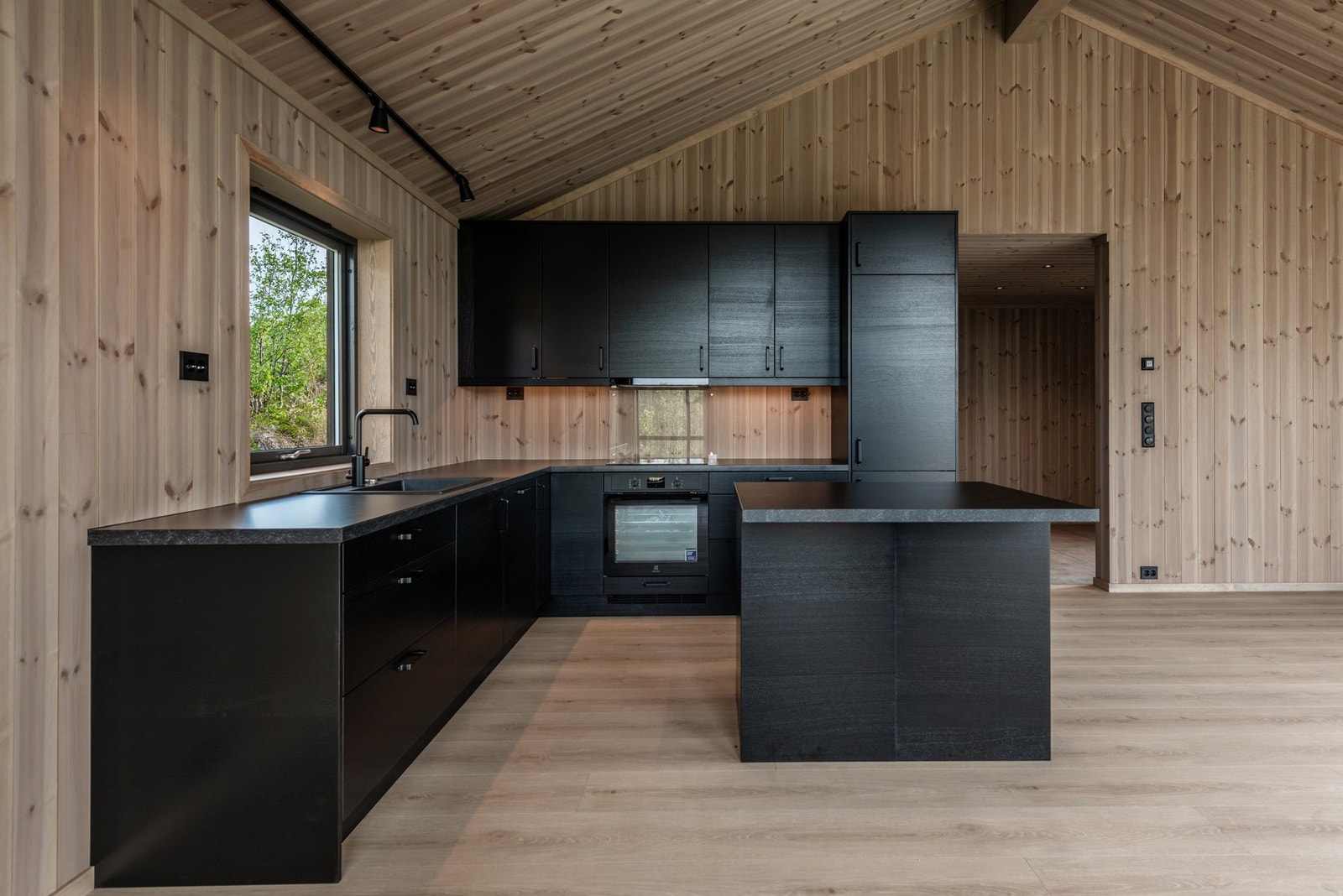 Kjøkkenet har mørke fronter og integrerte hvitevarer. Galleribilde