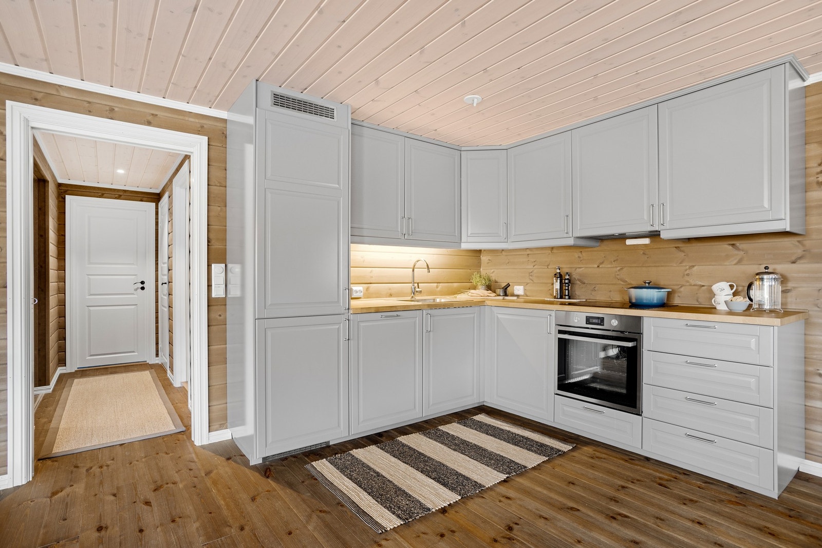 Kjøkkenet har integrerte hvitevarer som platetopp, stekeovn, oppvaskmaskin og kjøleskap Galleribilde