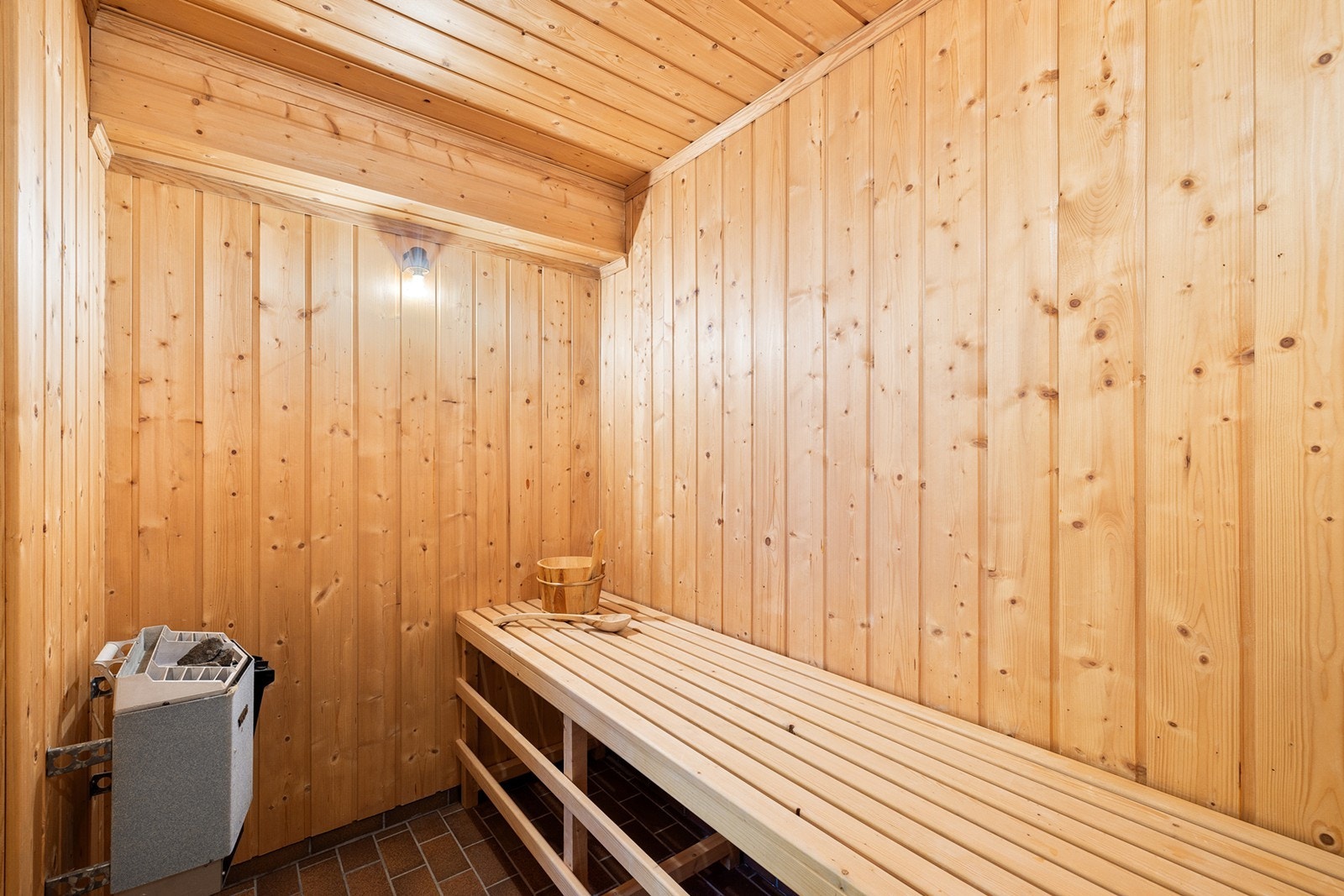 Badstuen har fliser på gulv, panel på vegger og himling. Det er montert badstuovn (fra byggeår). Galleribilde