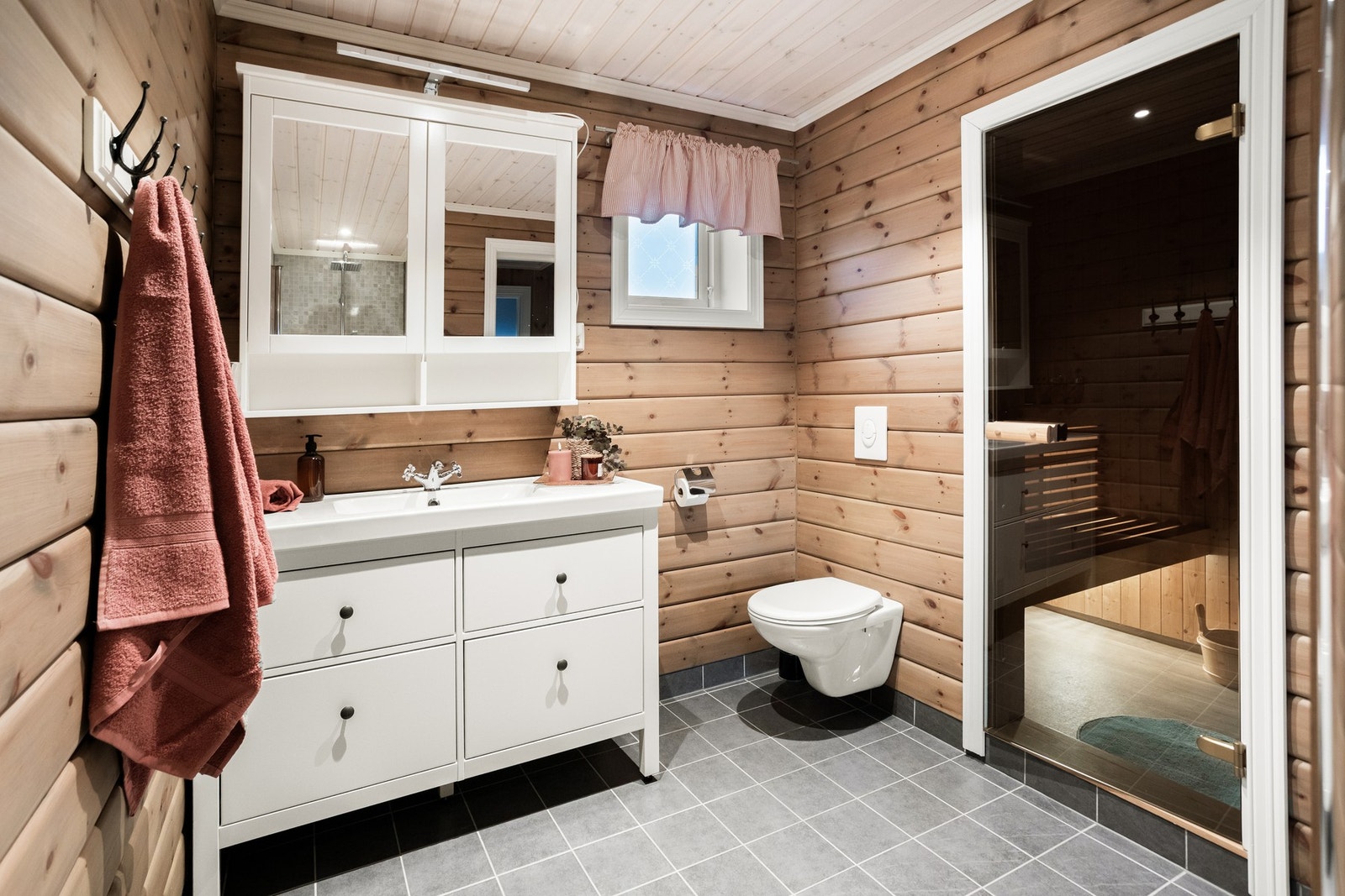 Badet fremstår som moderne, med fliser i dusjsonen og trepanel på øvrige vegger som gir en lun og rustikk atmosfære. Galleribilde