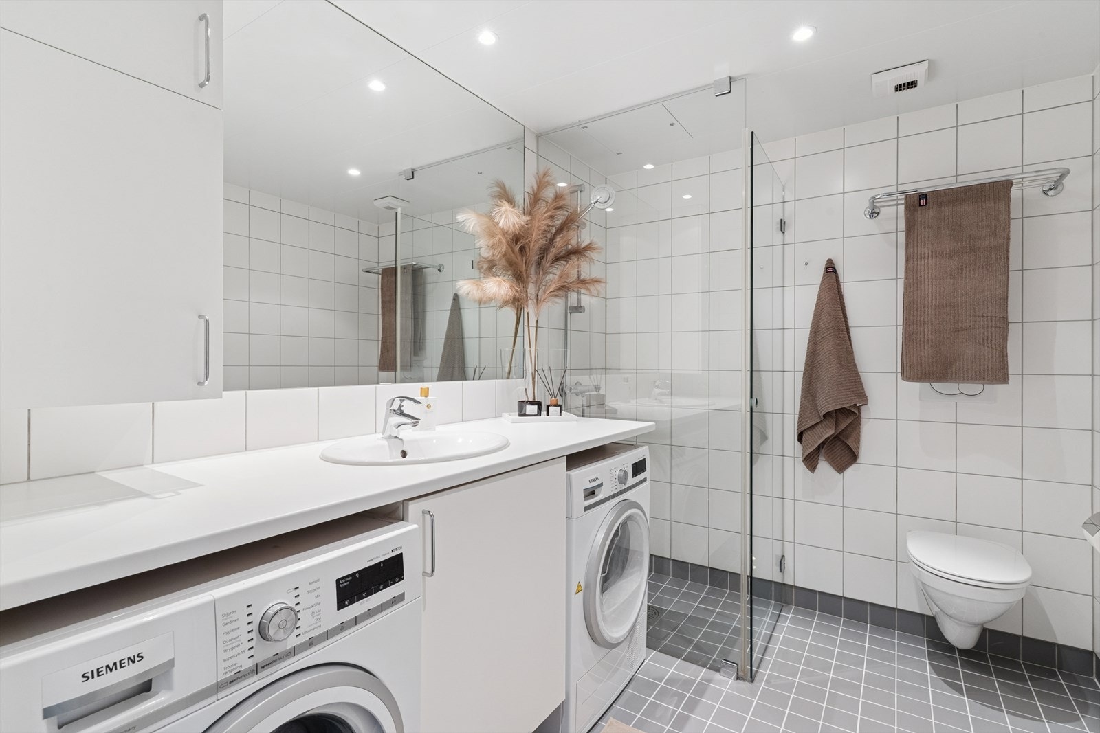 Badet fremstår som stilrent og romslig, med fliser på både gulv og vegger som gir et moderne og helhetlig uttrykk Galleribilde
