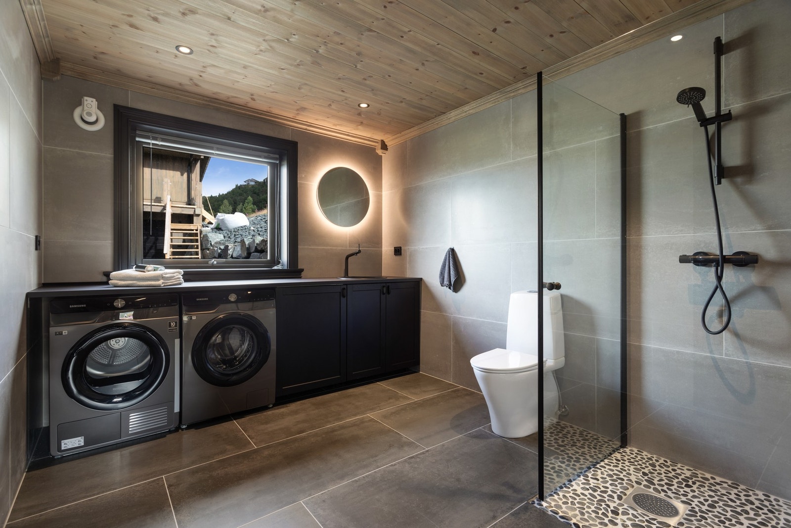 Hyttas andre bad finnes i underetasjen. Inneholder dusjnisje med glassdører, toalett og praktisk arbeidsbenk med nedfelt servant, oppbevaringsplass og opplegg til vaskemaskin og tørketrommel Galleribilde