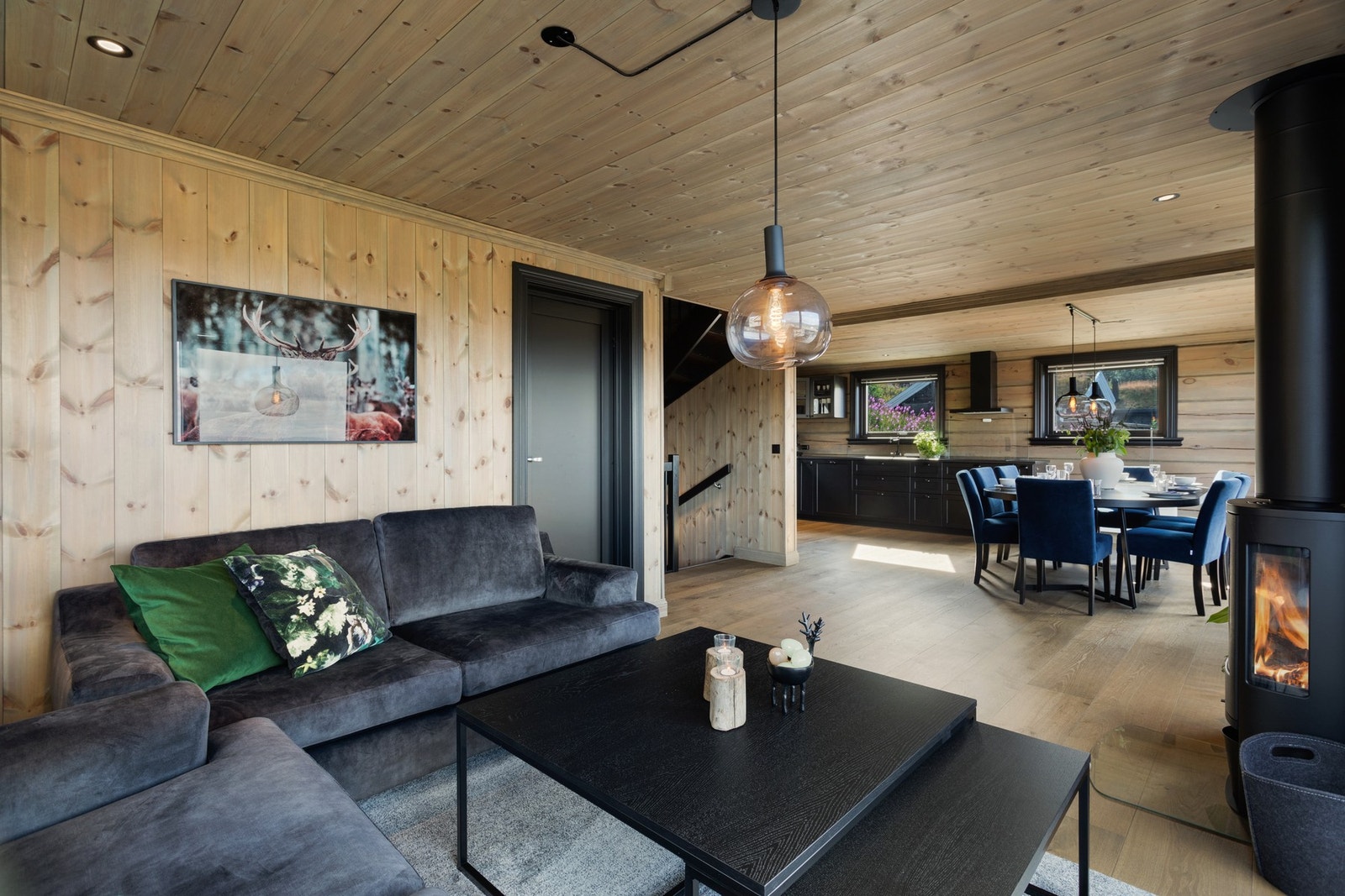 Stue og kjøkken i åpen løsning. Stuedelen er romslig og åpner opp for flere møbleringsmuligheter. Peisen står sentralt i rommet og flammene kan sees fra flere vinkler Galleribilde