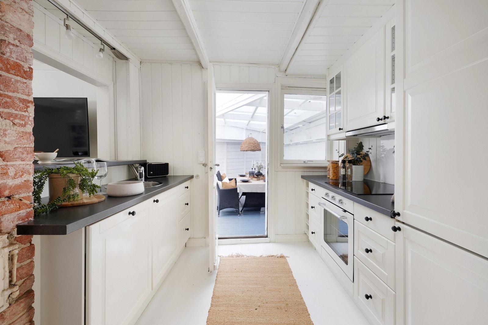 Pent kjøkken fra 2013 med integrerte hvitevarer og utgang til terrasse Galleribilde