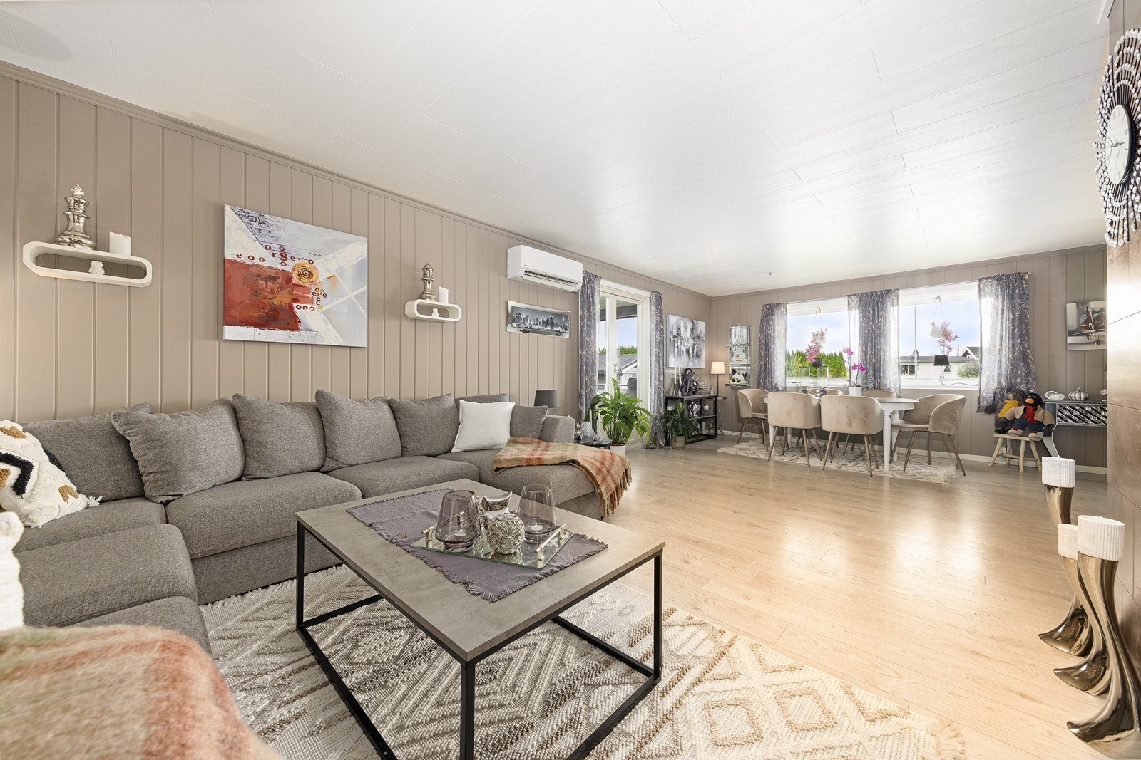 Lys og moderne stue med 1-stavs laminat på gulv og malt panel på vegg i en trendy og delikat fargetone. Galleribilde