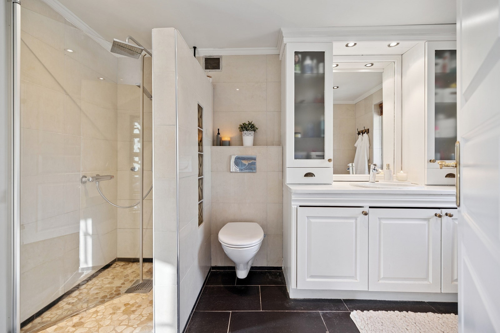 Badet i første etasje er flislagt og utstyrt med dusjnisje, vegghengt toalett og servant med oppbevaring. Galleribilde