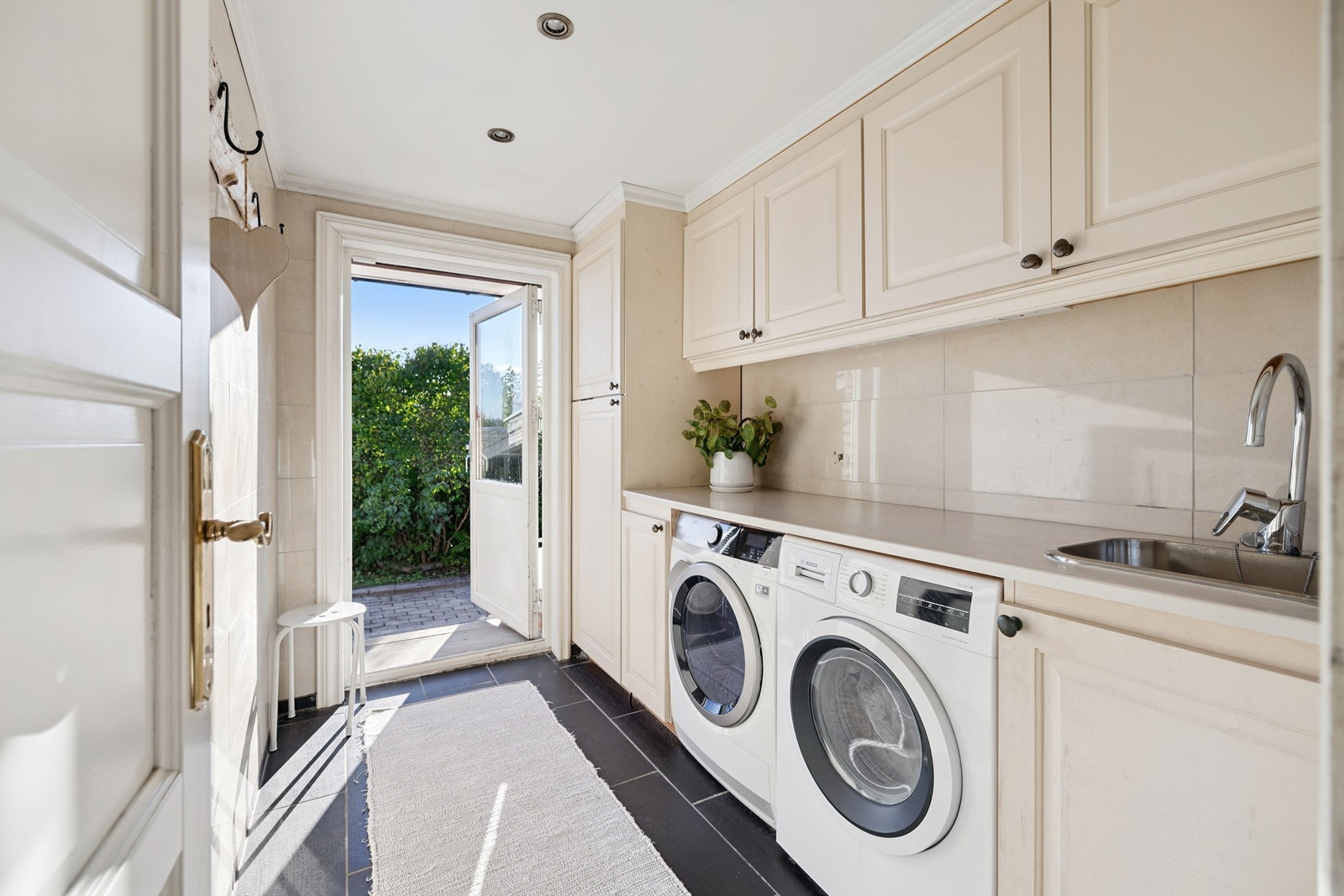 Et praktisk vaskerom med egen utgang, innredning og opplegg for vaskemaskin. Galleribilde