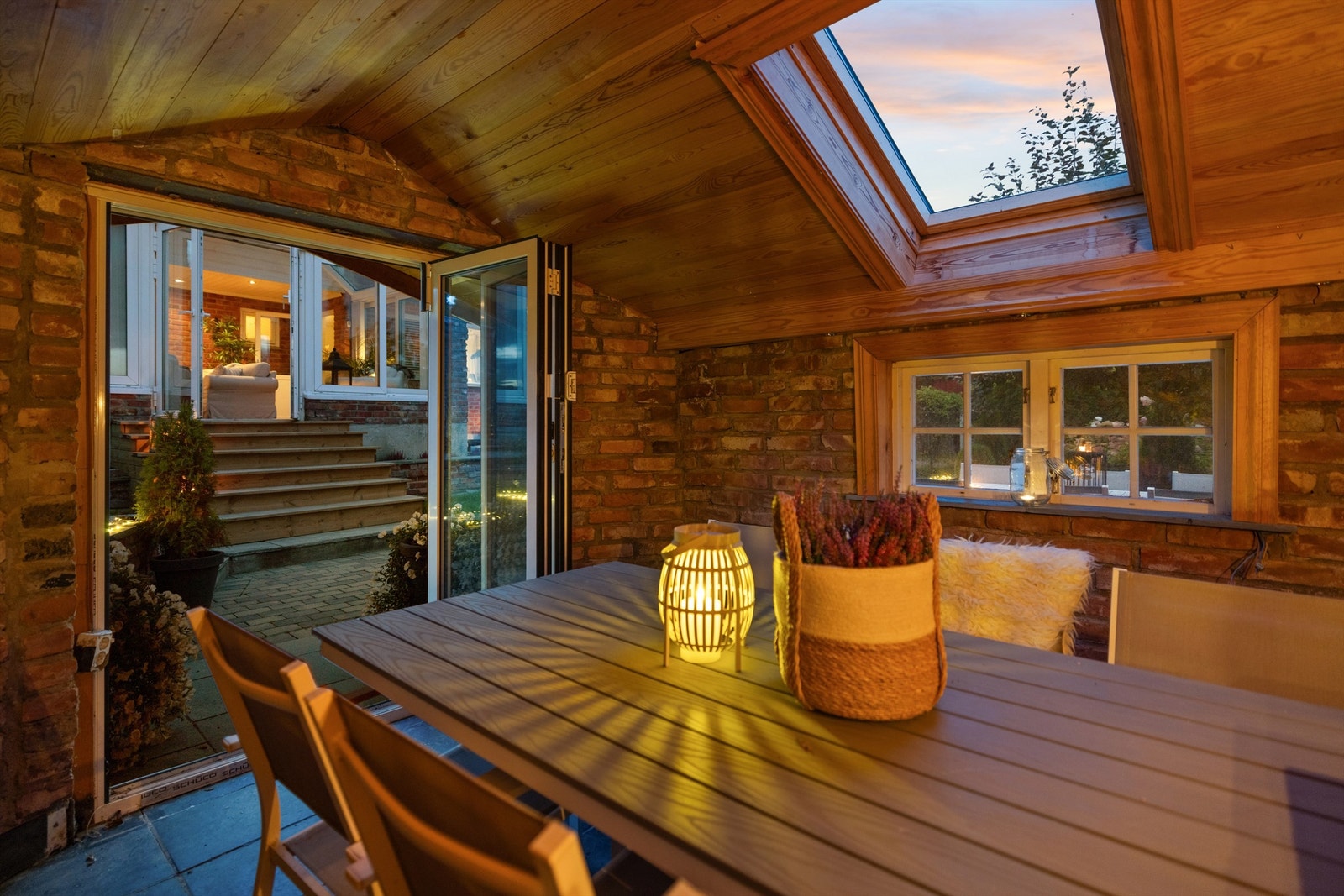 Den separate hagestuen har foldedører som kan åpnes helt opp mot uteplassen. Galleribilde