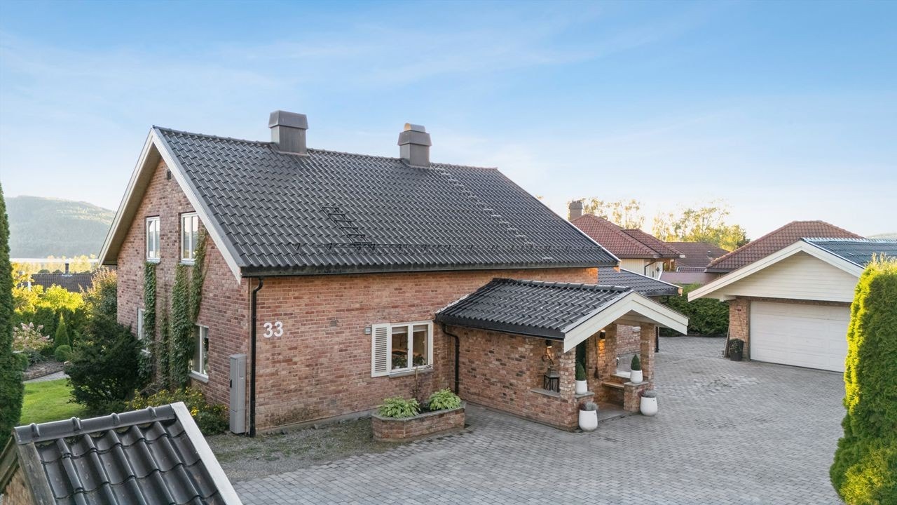 Pent opparbeidet gårdsplass med belegningsstein og frittstående dobbelgarasje. Galleribilde