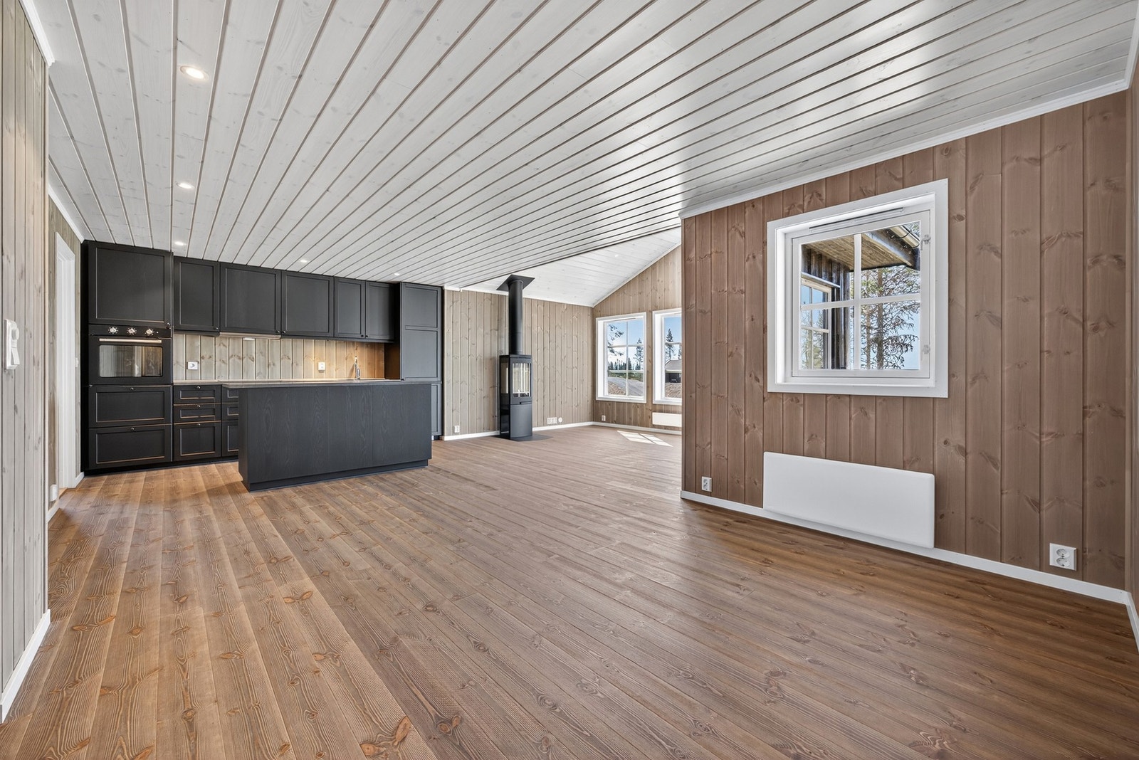 Gulv i stue, kjøkken, soverom og hems leveres med børstet furugulv i brun og veggene leveres med slettpanel i Myk Elegance og himlinger hvitpigmentert. Illustrasjon er ikke av selve hytta. Galleribilde