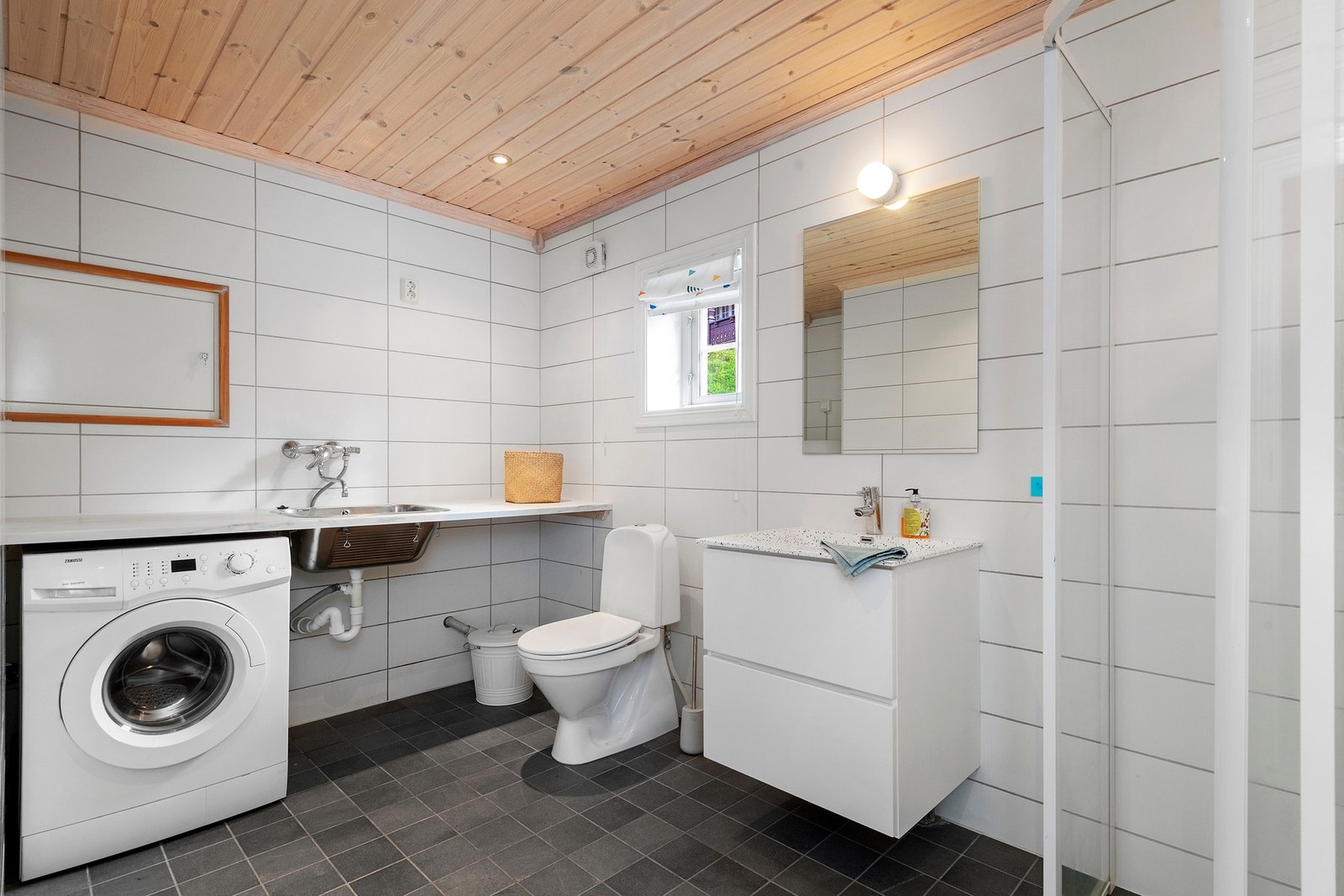 Flislagt bad/vaskerom med opplegg til vaskemaskin og praktisk benk med utslagsvask. Galleribilde