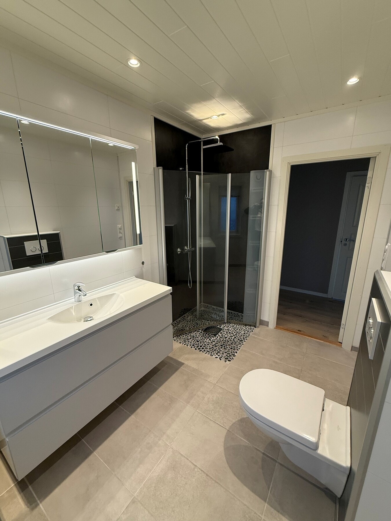 Badet har dusjhjørne med regnfallsdusj og innfellbare dusjvegger. Dusjsonen (gulv, veger og tak) ble oppgradert i September. Galleribilde