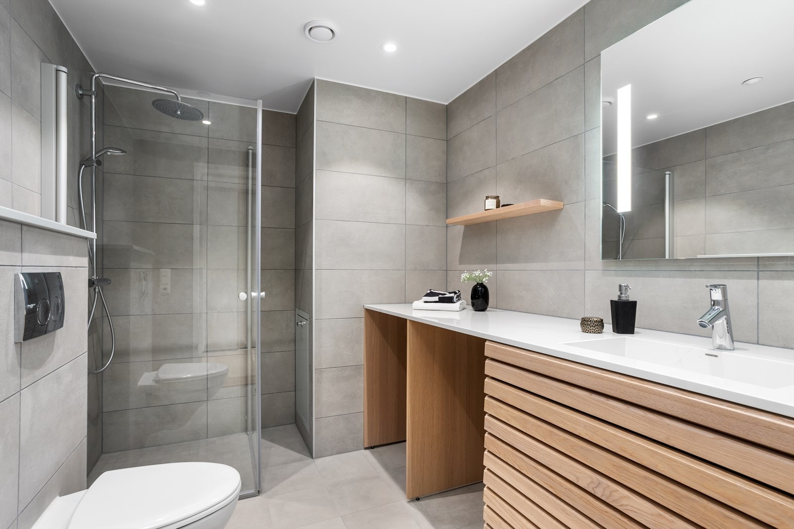 På baderommet med opplegg for vaskemaskin og tørketrommel er det ekstra langstrakt benkeplate og elegant løsning hvor vaskemaskinen og tørketrommelen kan plasseres under benkeplaten. Galleribilde