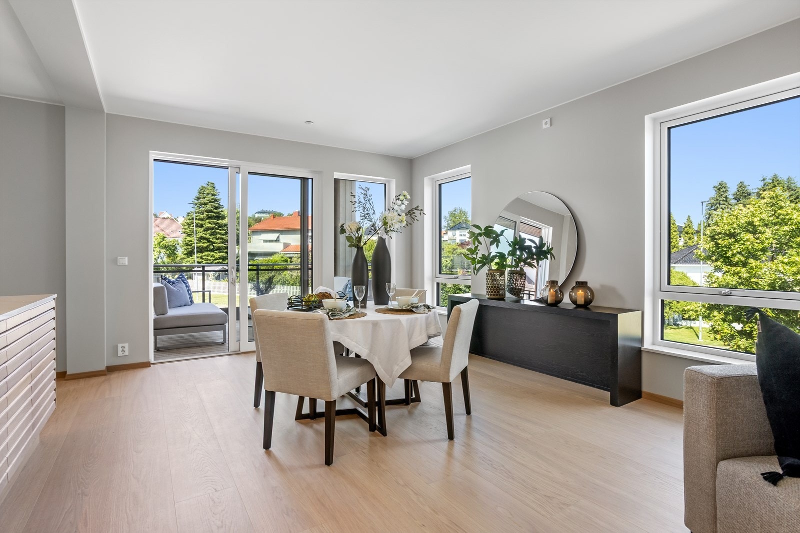 De store og dype vindusflatene gir flott lysinnfall og ikke minst en herlig nærkontakt med uterommet hvor forskjellen mellom innerom og uterom nærmest på et elegant vis viskes ut. Den høyreiste skyvedøren leder ut til balkongen. Galleribilde