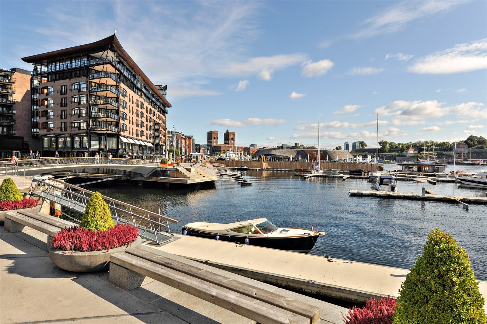Aker Brygge med sine ikoniske bygg, marina og utsikt mot Oslo Rådhus. Galleribilde