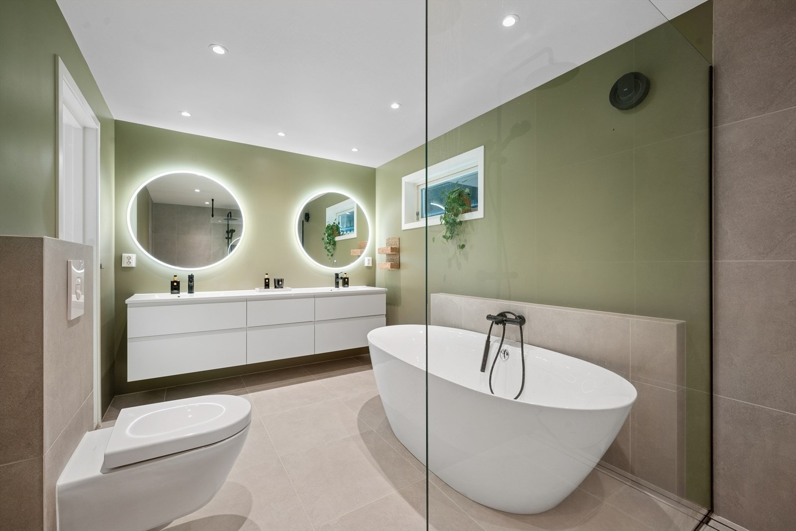 Rommet er av god størrelse, og inneholder både dobbel dusj og badekar til glede for store og små. Videre inneholder badet vegghengt toalett og dobbel innredning med nedfelt servant. Galleribilde