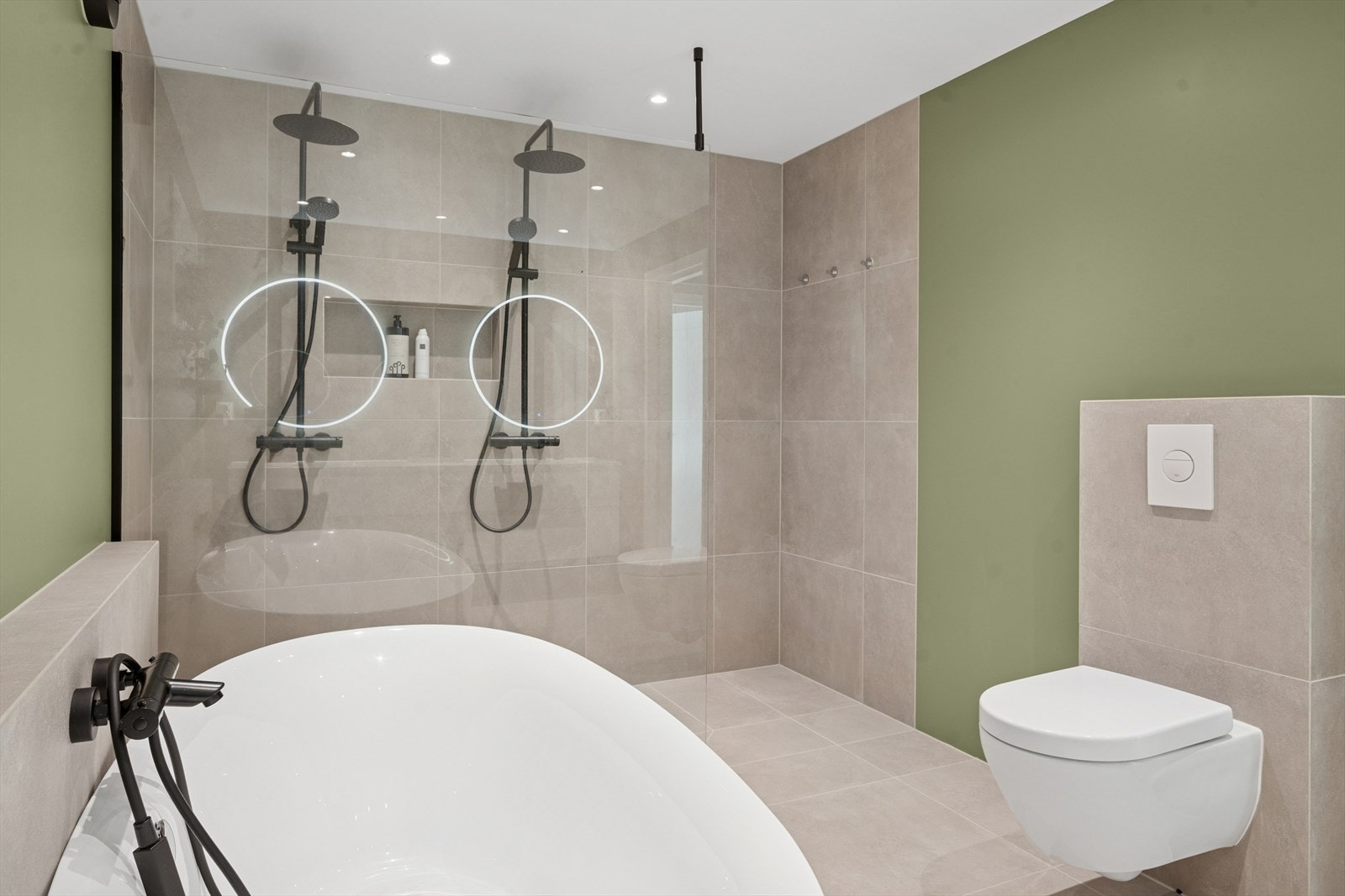 Badets vegger har malte flater i en moderne grønntone, samt fliser ved dusj, toalett og badekar. I samme utførelse som flis på vegg, har badet flislagt gulv med 60 x 60 fliser med varmekabler. Galleribilde