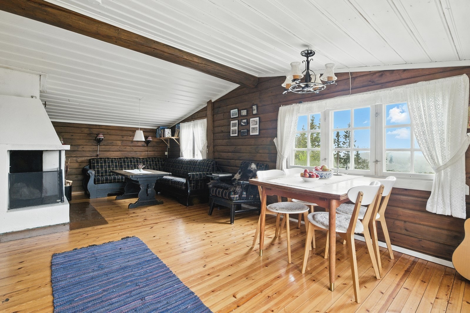 Hytta har en koselig stue med liggende tømmervegger i varme fargetoner som gir et lunt og levende uttrykk. Galleribilde