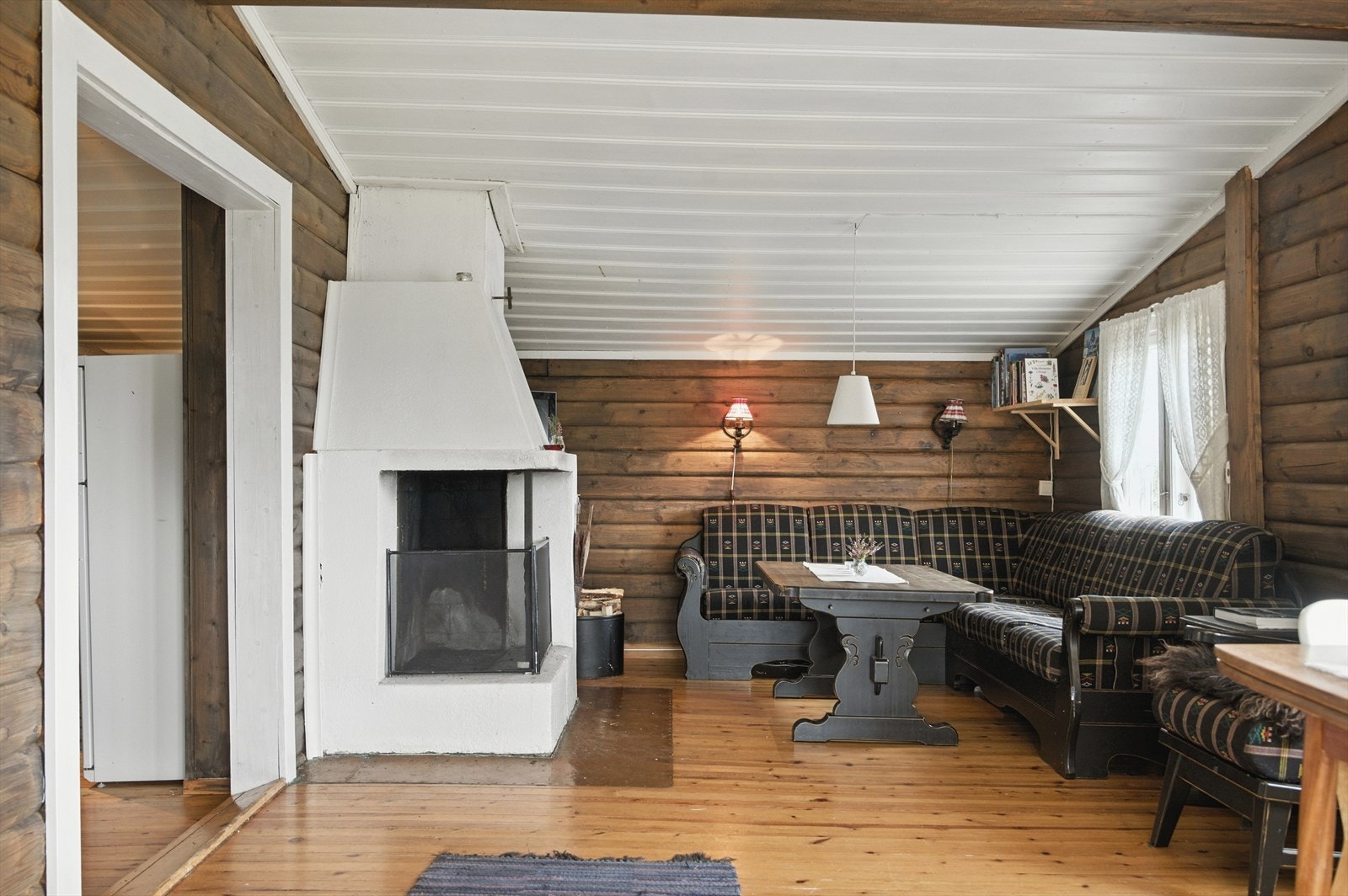 Her er det en sofakrok ved den åpne peisen som innbyr til kos og hygge. Inntil peisen er det også etablert en liten Jøtul vedovn. Galleribilde