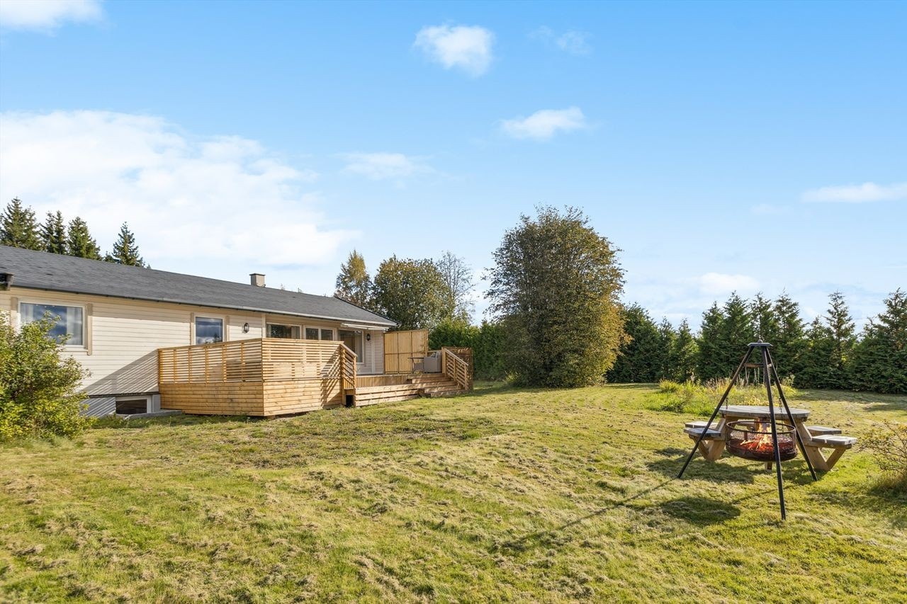 Eiendommen har en stor hage med plen og variert beplantning, med god plass for utendørsaktiviteter. Galleribilde