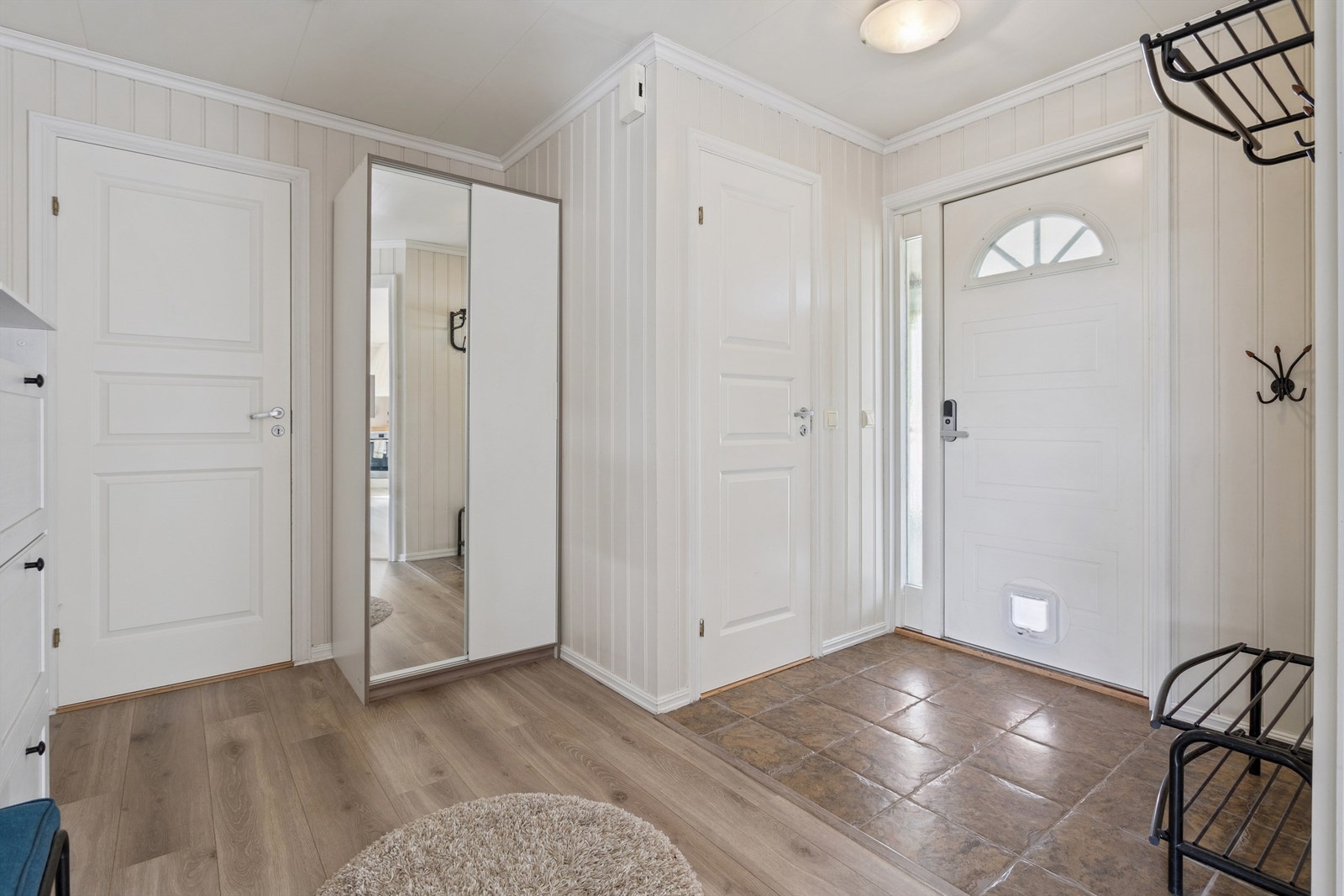 Vi starter i en lys entré med praktiske fliser på gulvet og tilgang til flere av etasjens rom. Galleribilde