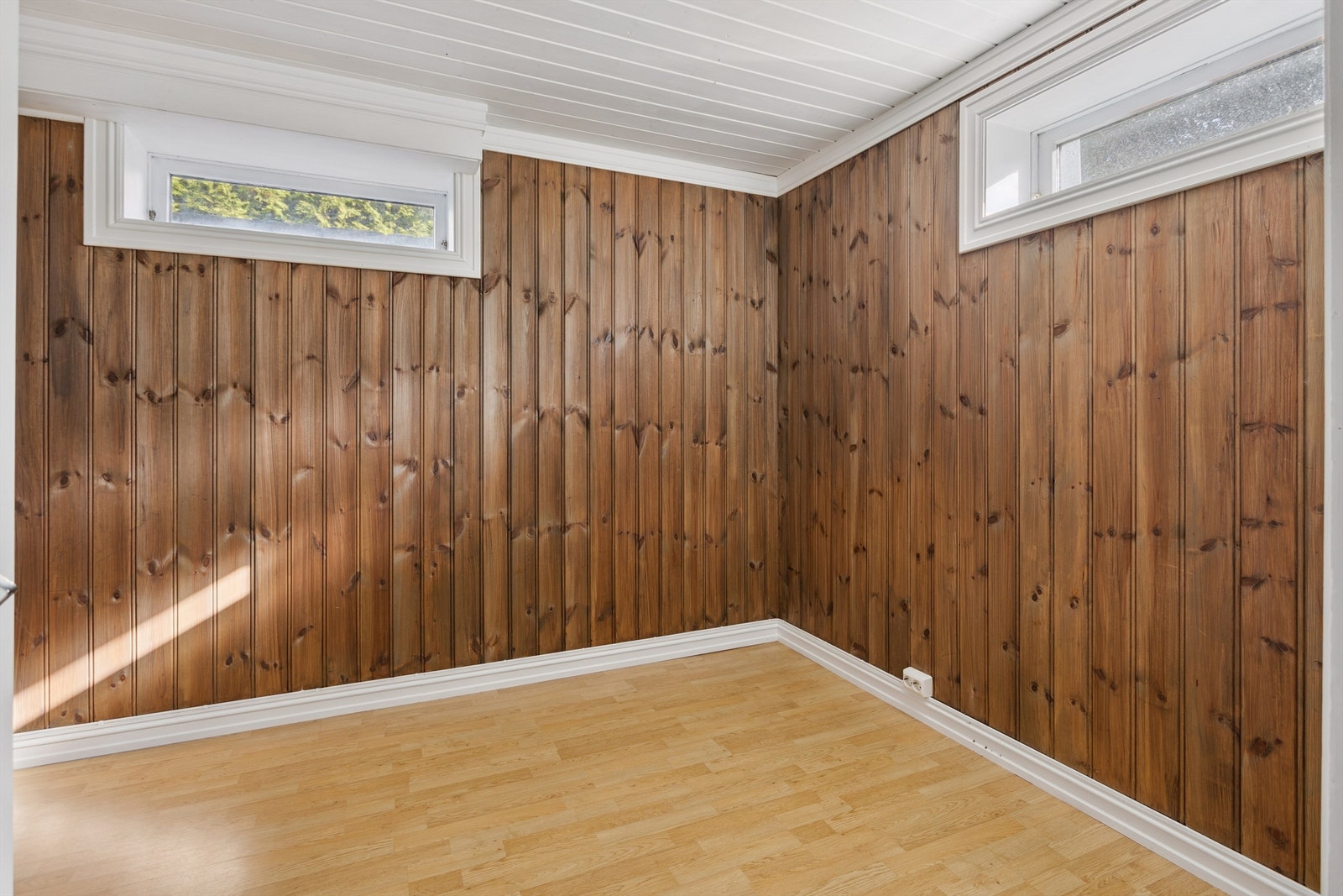 Kjelleren har flere rom med potensial, her med laminatgulv og panel på veggene. Galleribilde