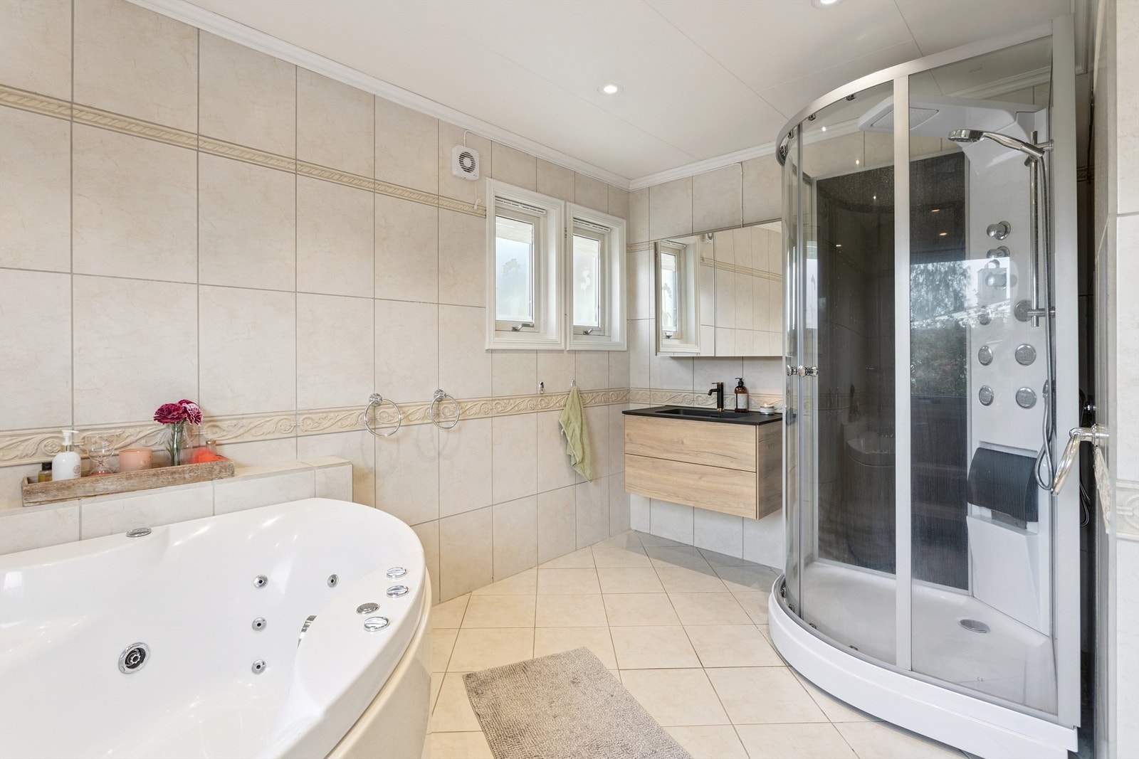 Badet i første etasje er helfliset og utstyrt med både dusjkabinett og boblebadekar. Galleribilde