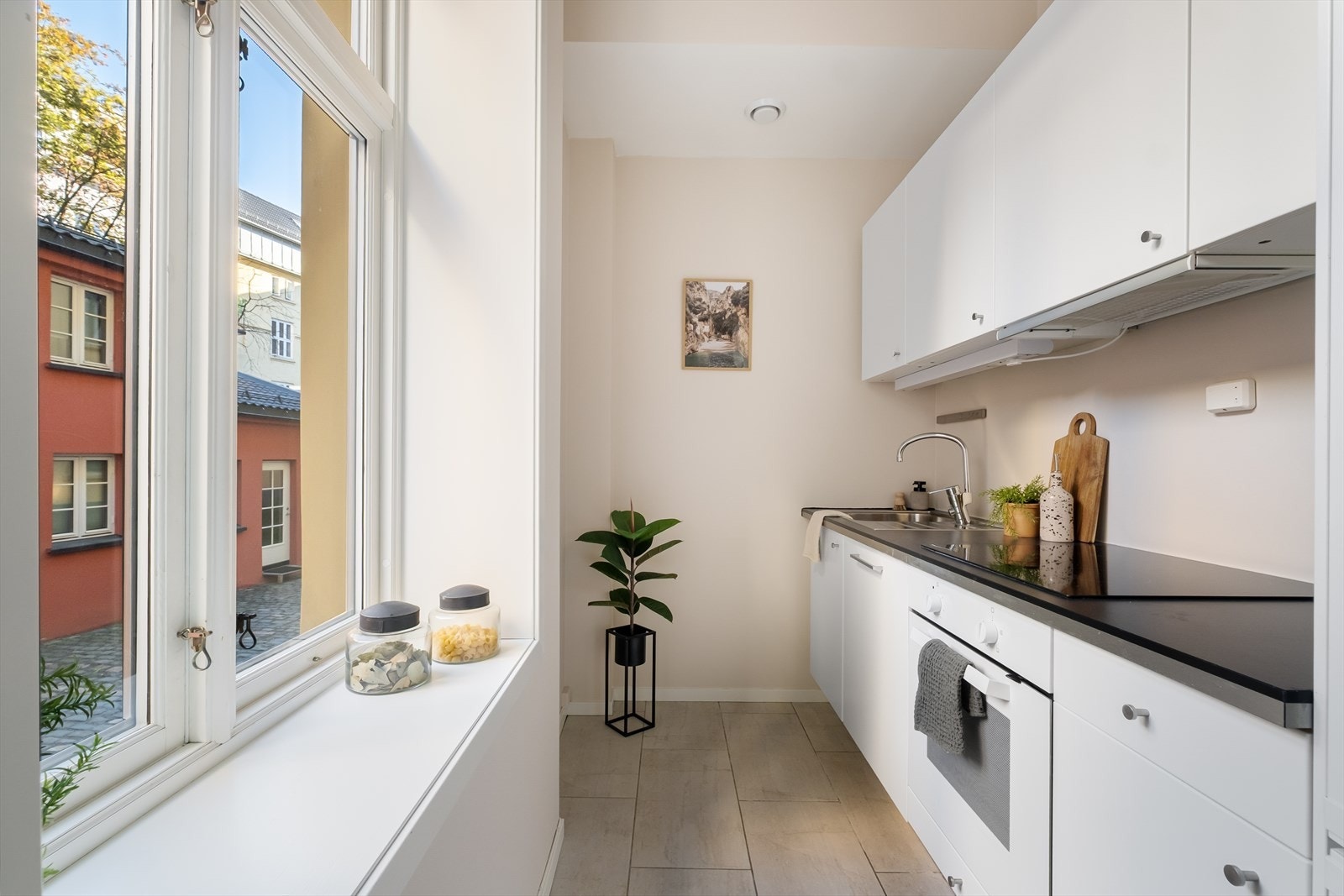 Tidsriktig glatt innredning fra IKEA, soft close, armatur, laminat benkeplate med nedfelt stålkum og keramisk topp, integrert komfyr, oppvaskmaskin (smal type), kjøl/frys. Galleribilde