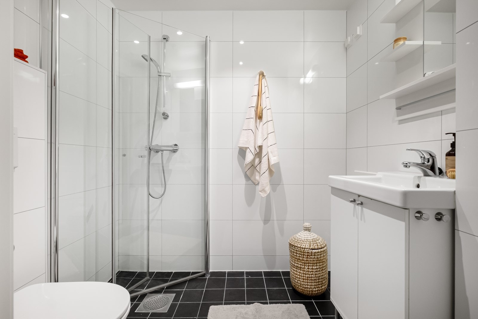 Flislagt baderom fra rundt 2015 med varmekabler, avtrekk, speil, armatur, downlights, opplegg for vaskemaskin, servant med innredning, dusj hjørne med innfellbare glassdører, vegghengt toalett. Galleribilde