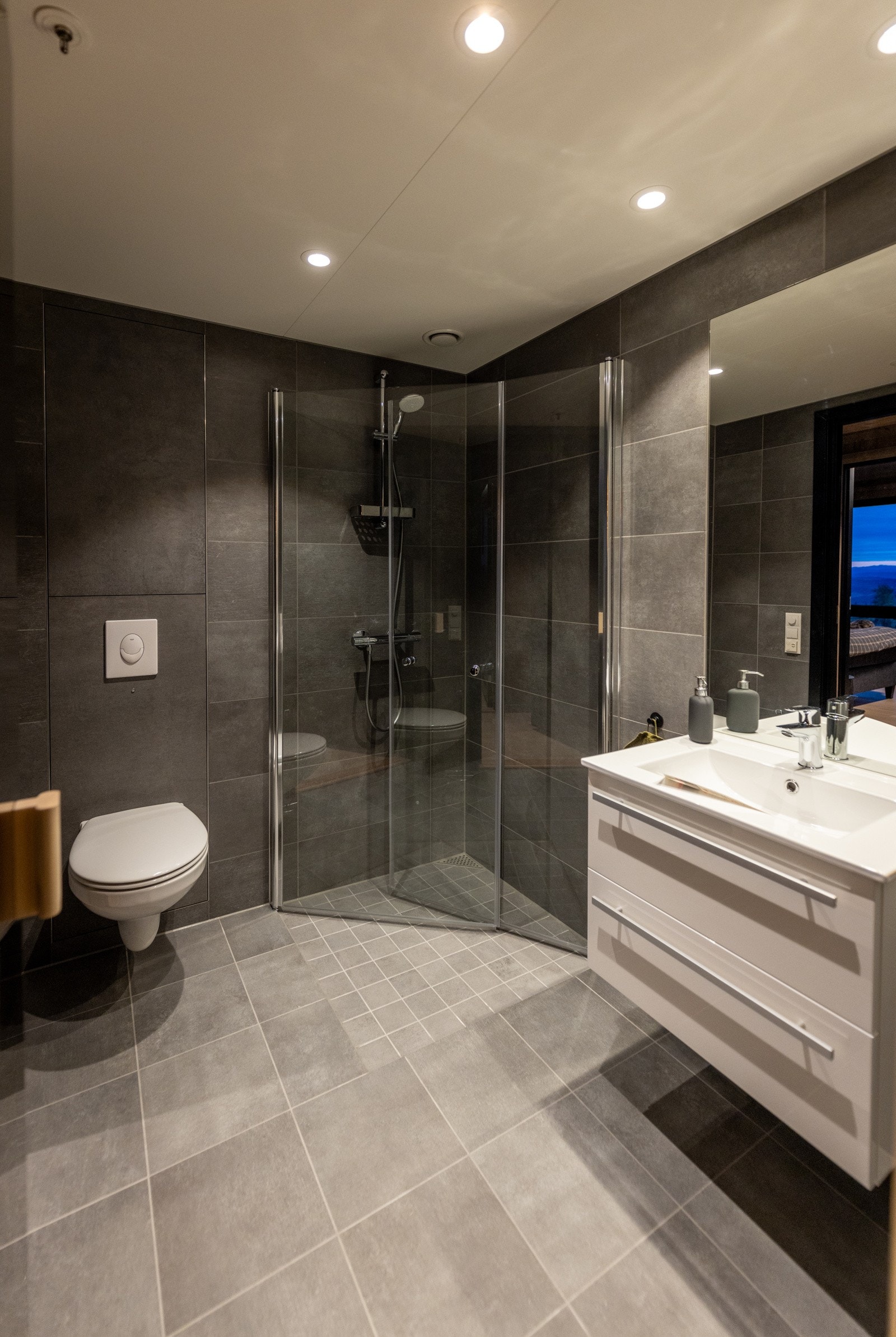 Det største badet er utstyrt med vegghengt toalett, dusj med glassvegger, servant med innredning og speil. Galleribilde